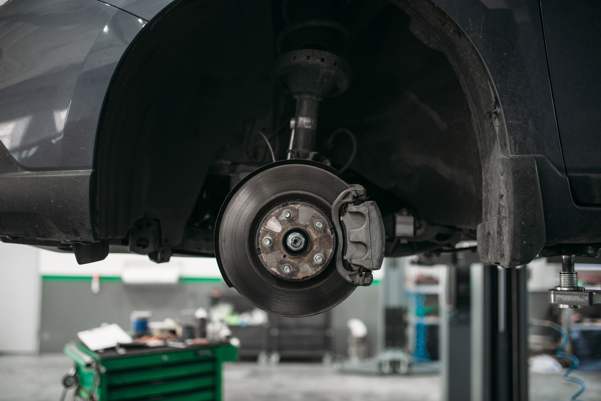A car is sitting on a lift in a garage.