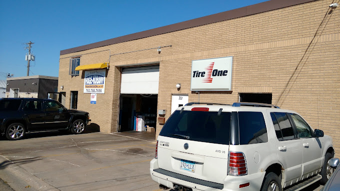 A white suv is parked in front of a tire shop.