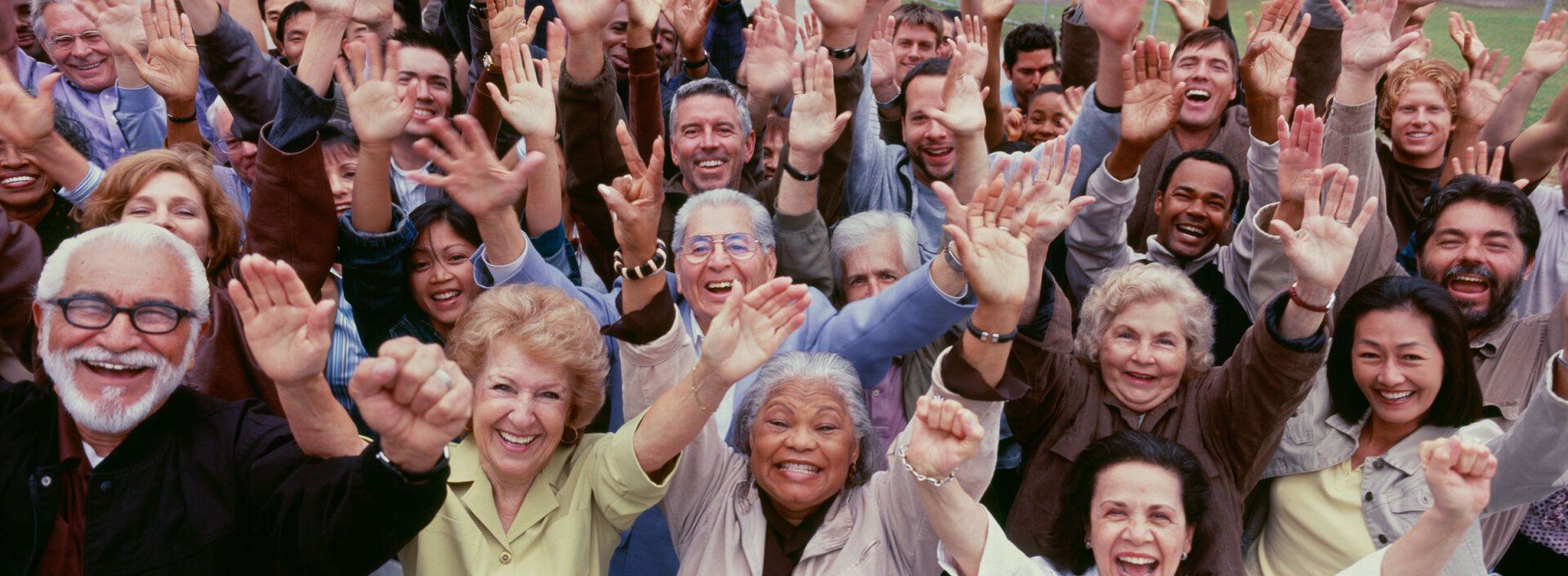 A diverse group of people with arms raised in a joyful gesture.