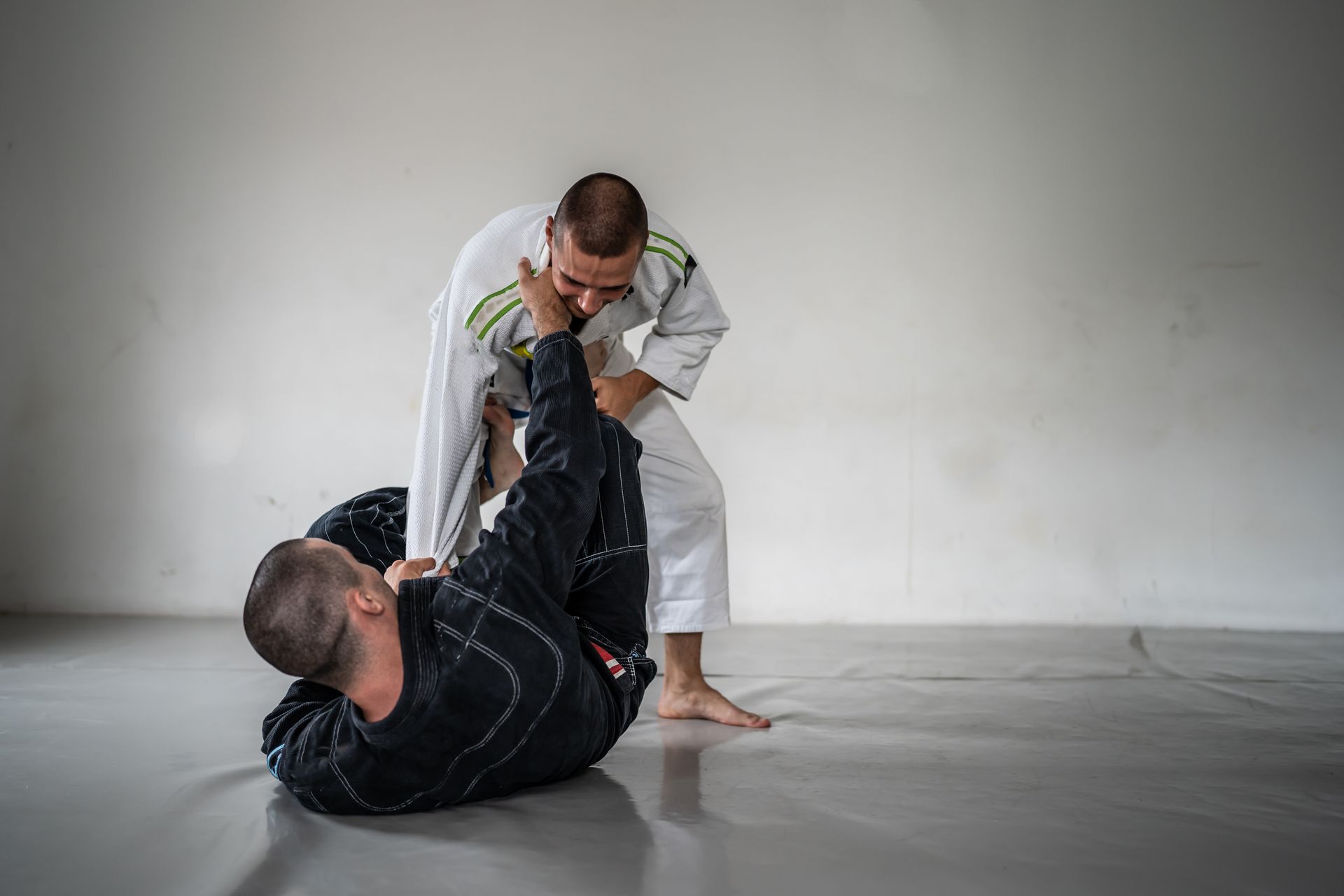 Two BJJ athletes drilling a ground grappling and leg control technique.
