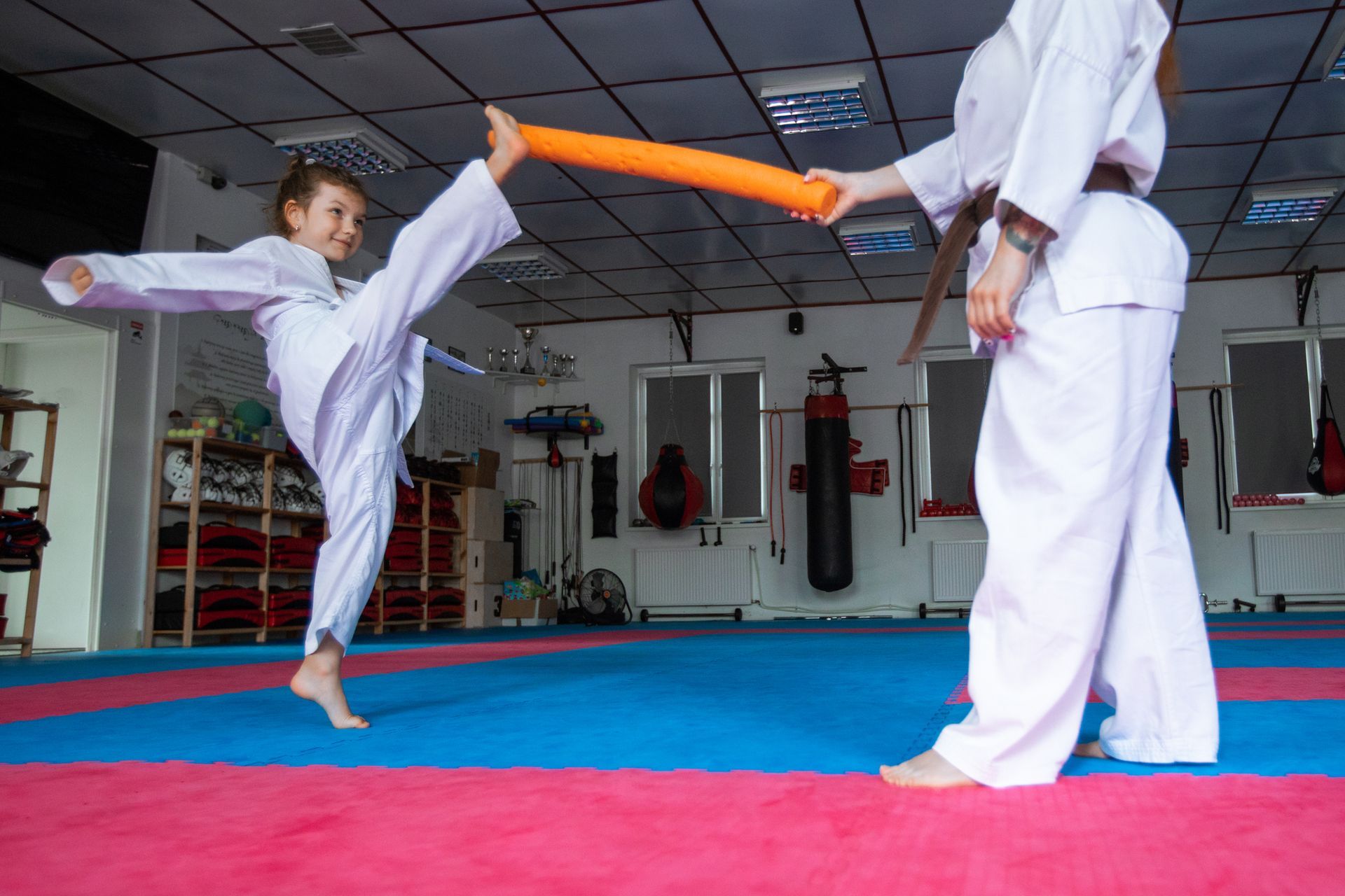 A girl training in karate with an orange stick, highlighting her dedication to martial arts classes.