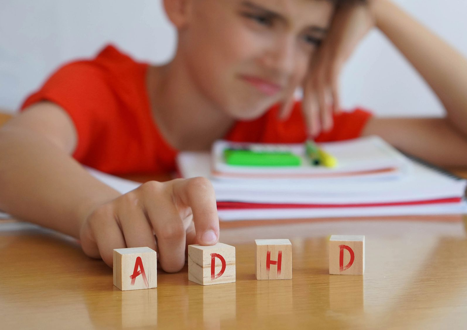 Un bambino che cerca di afferrare dei blocchi con le lettere su un tavolo in un'aula scolastica.