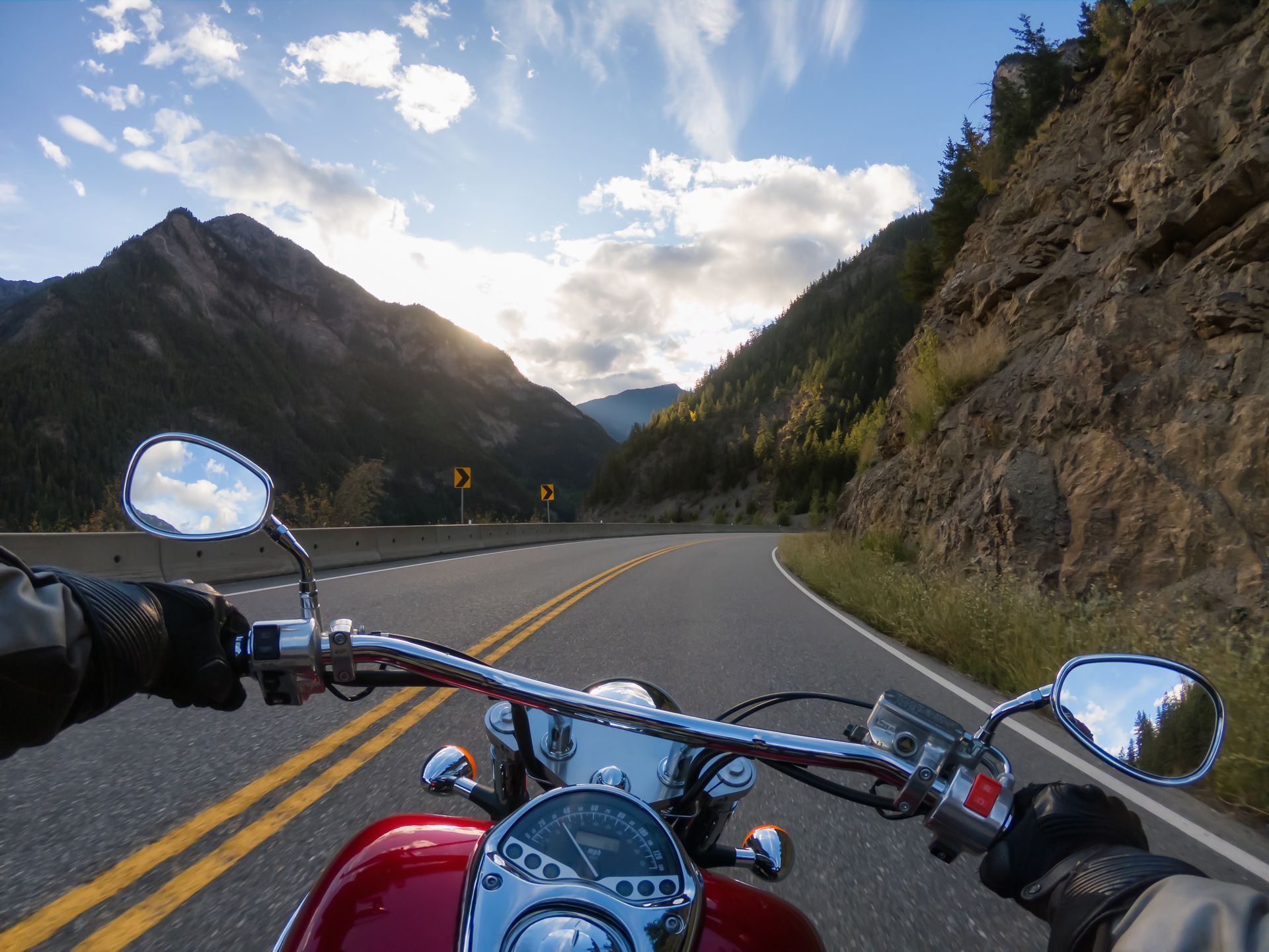 A person is riding a motorcycle down a mountain road.