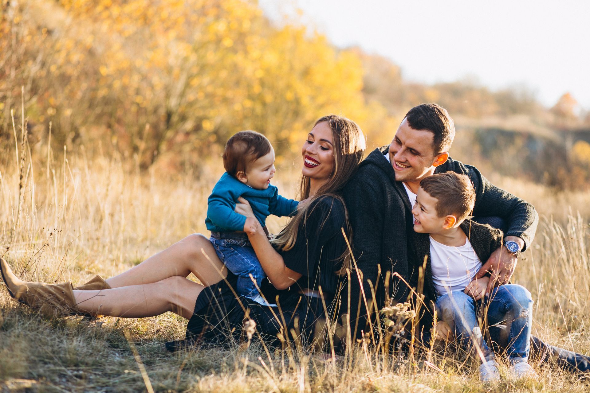 A family is sitting on the grass in a field.