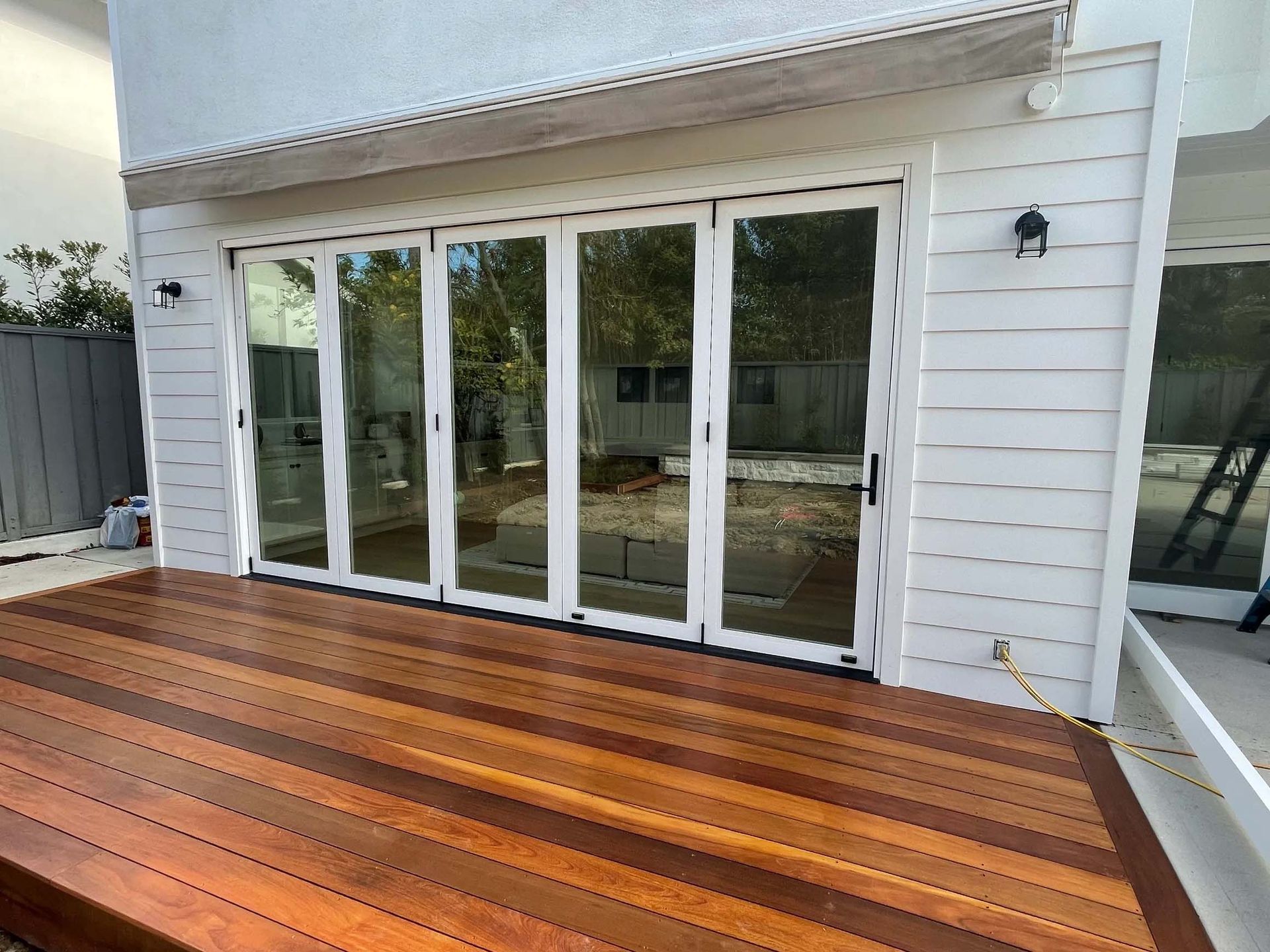 A wooden deck in front of a house with sliding glass doors.