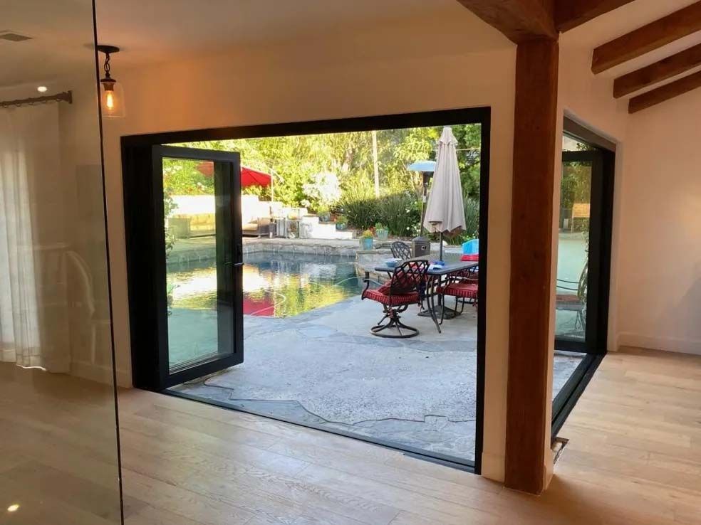 A room with a sliding glass door leading to a patio with chairs and umbrellas.
