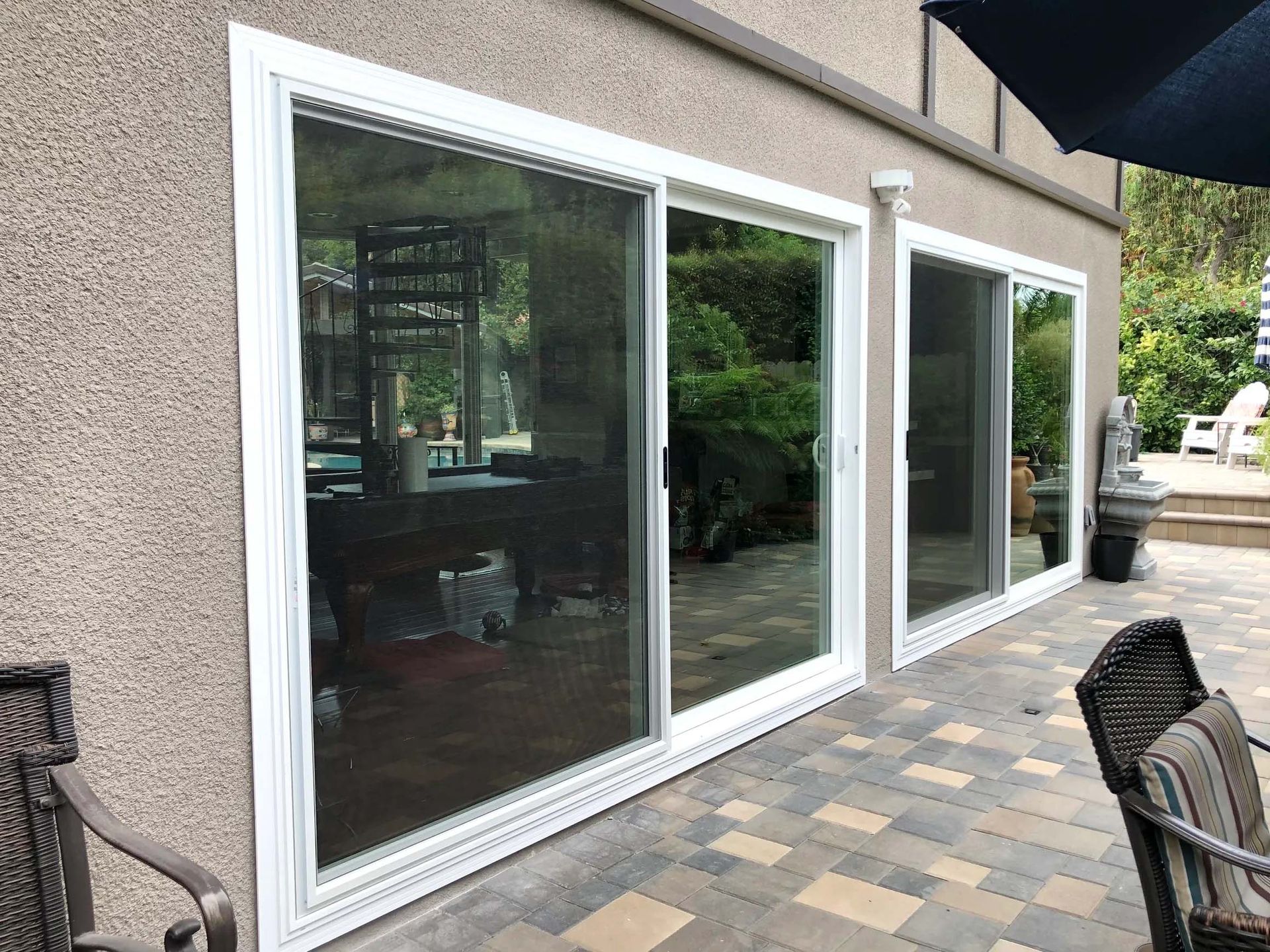 A house with sliding glass doors and a patio with chairs and umbrellas.