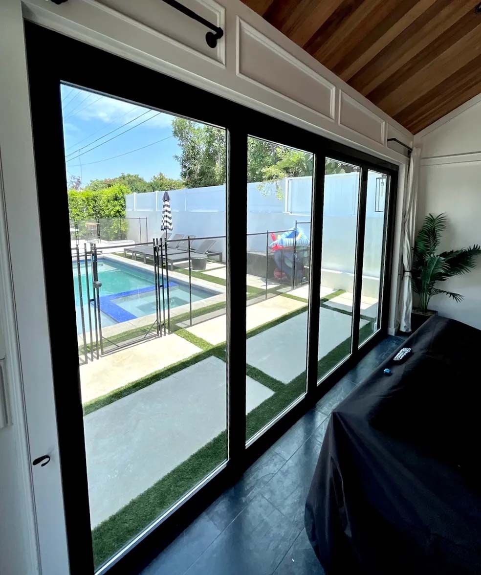 A room with a lot of windows and a pool in the background.
