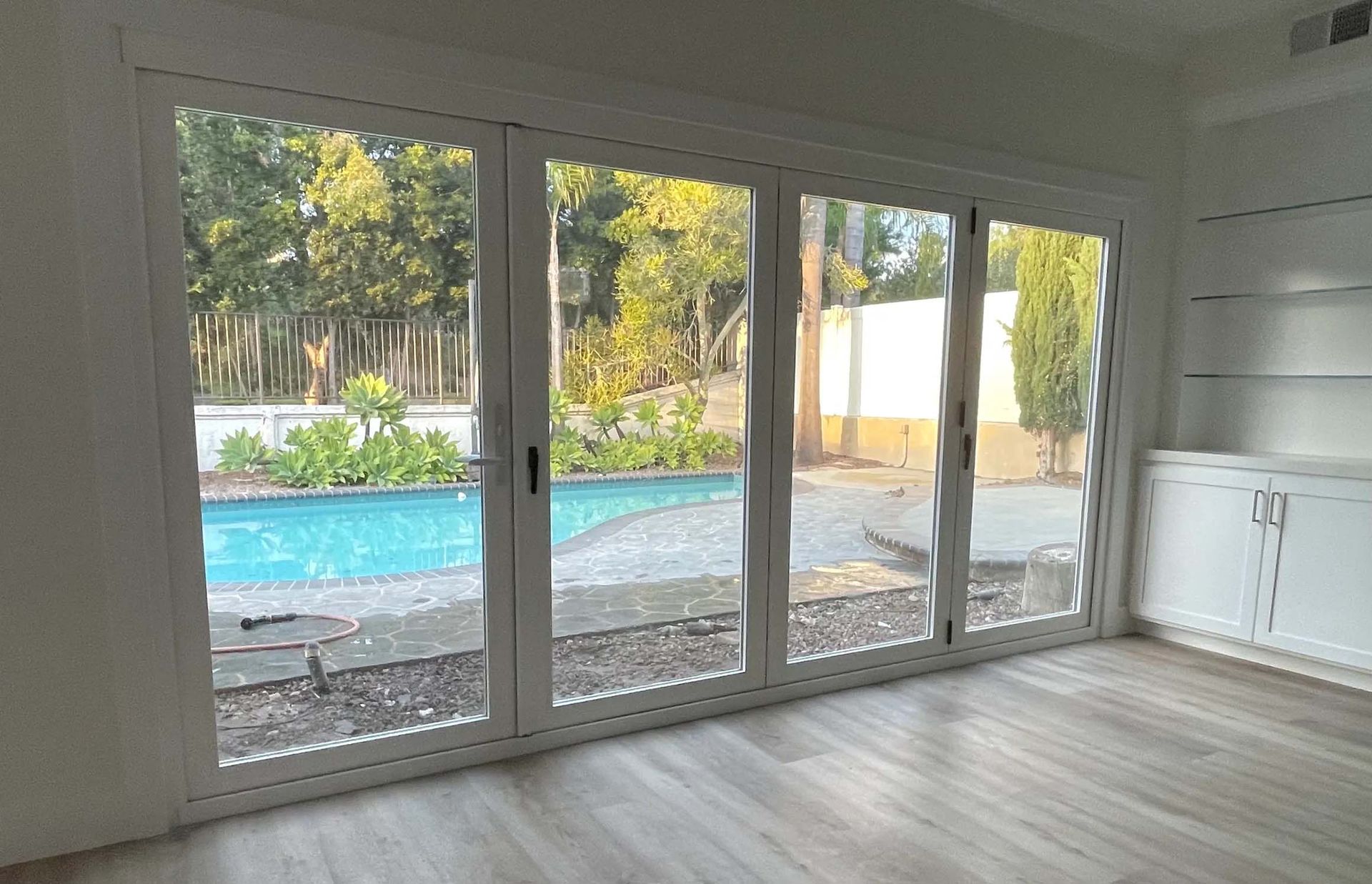 A room with a lot of windows and a pool in the background.
