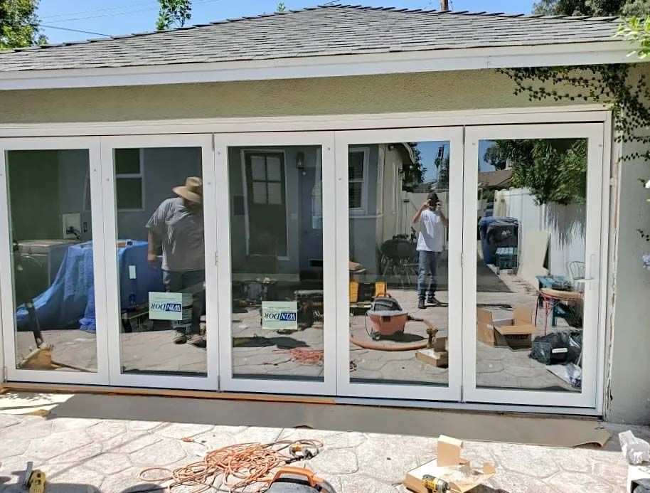 A man is standing in front of a house with a lot of windows.