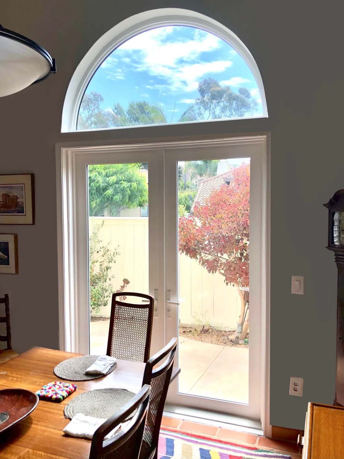A dining room with a table and chairs and a large window.