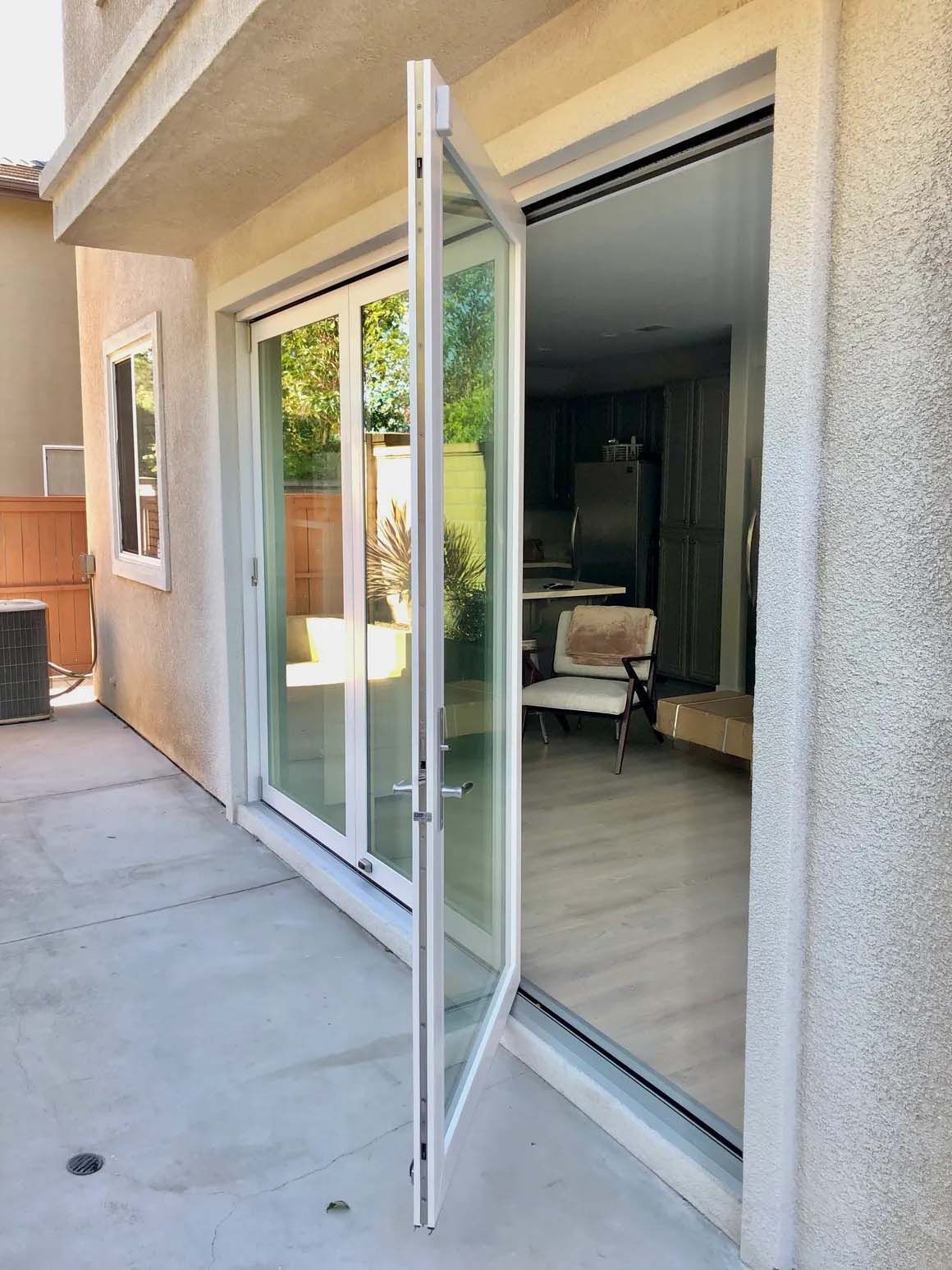 A white sliding glass door is open to a living room.
