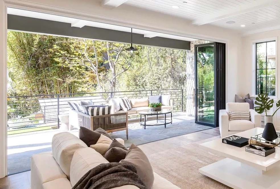 A living room with a couch , chairs , coffee table and sliding glass doors leading to a patio.