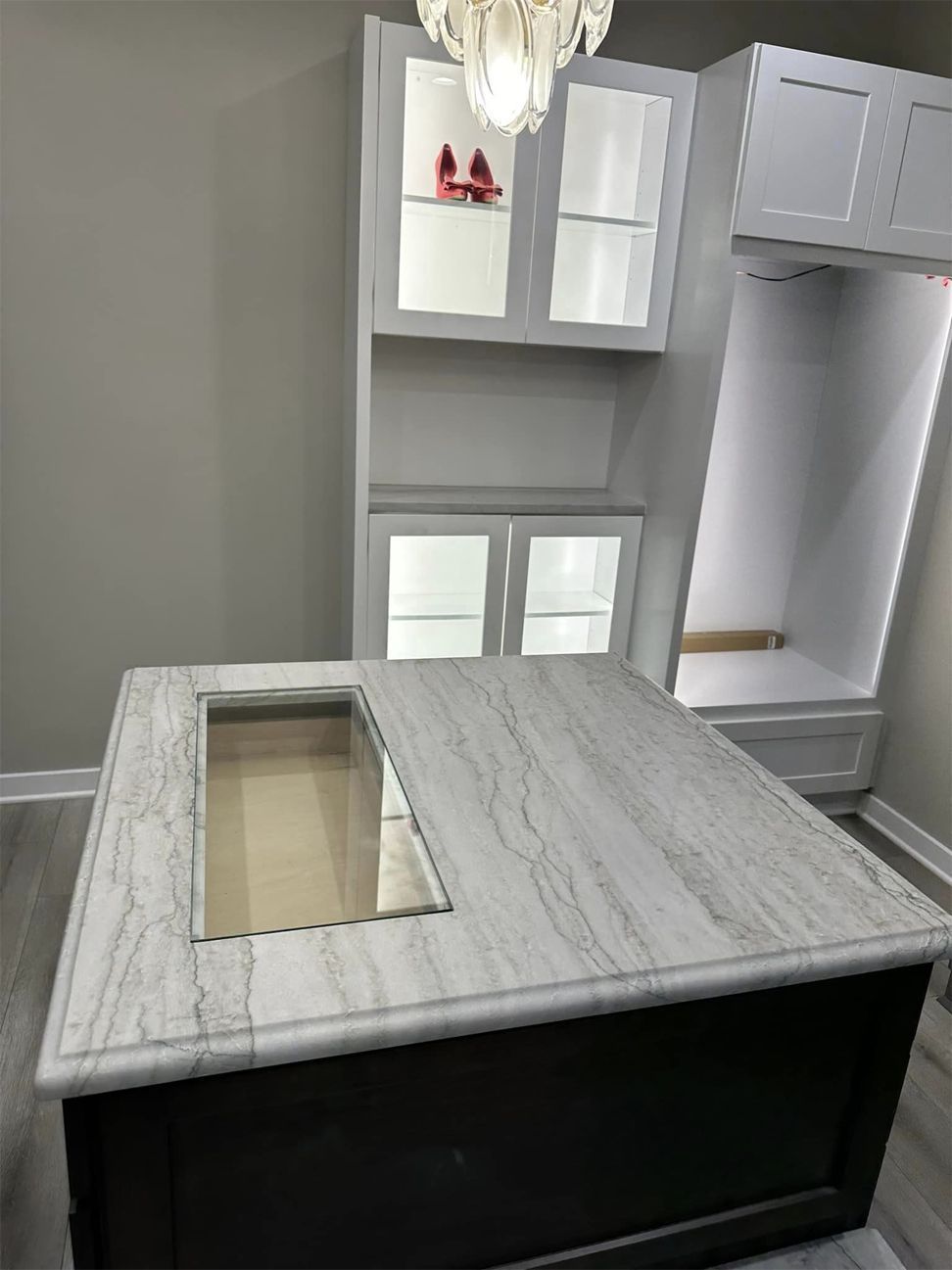 Kitchen island with gray marble top, cutout sink opening, and white cabinets in a modern kitchen