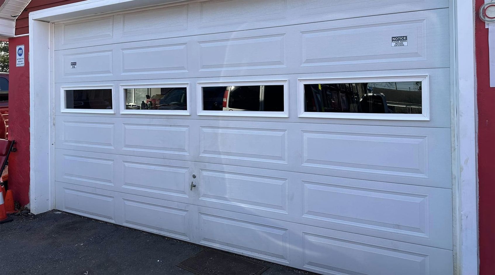 White residential garage door with four narrow windows and decorative paneling