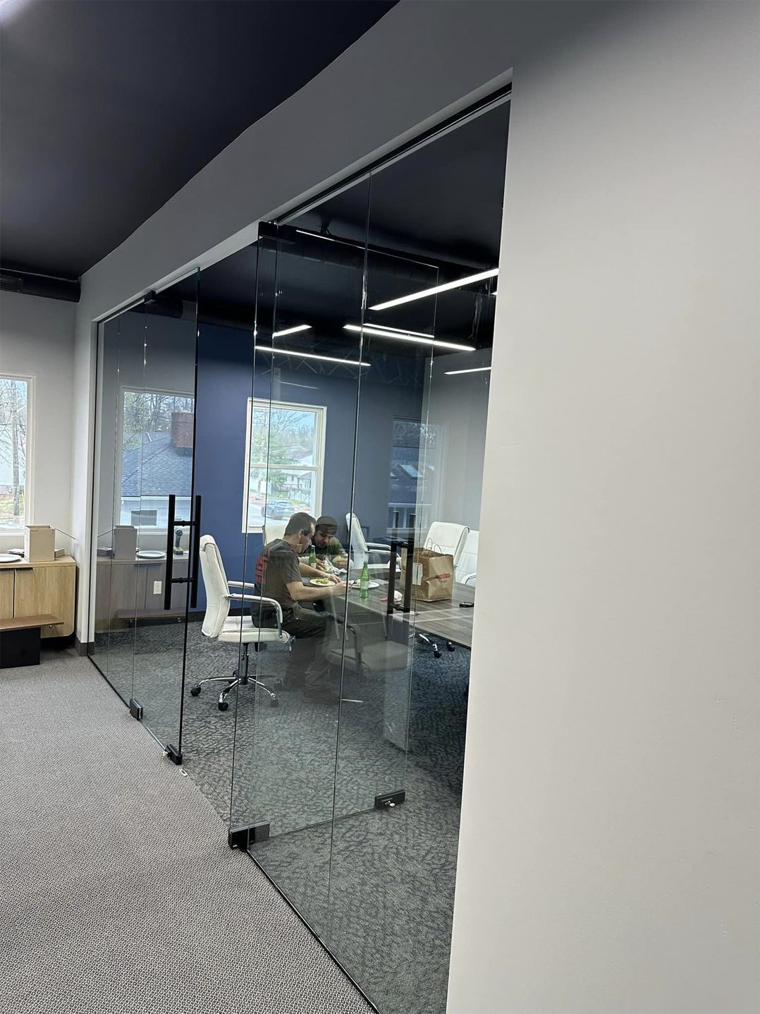 Glass-walled office with chairs around a table, seen through an open doorway.