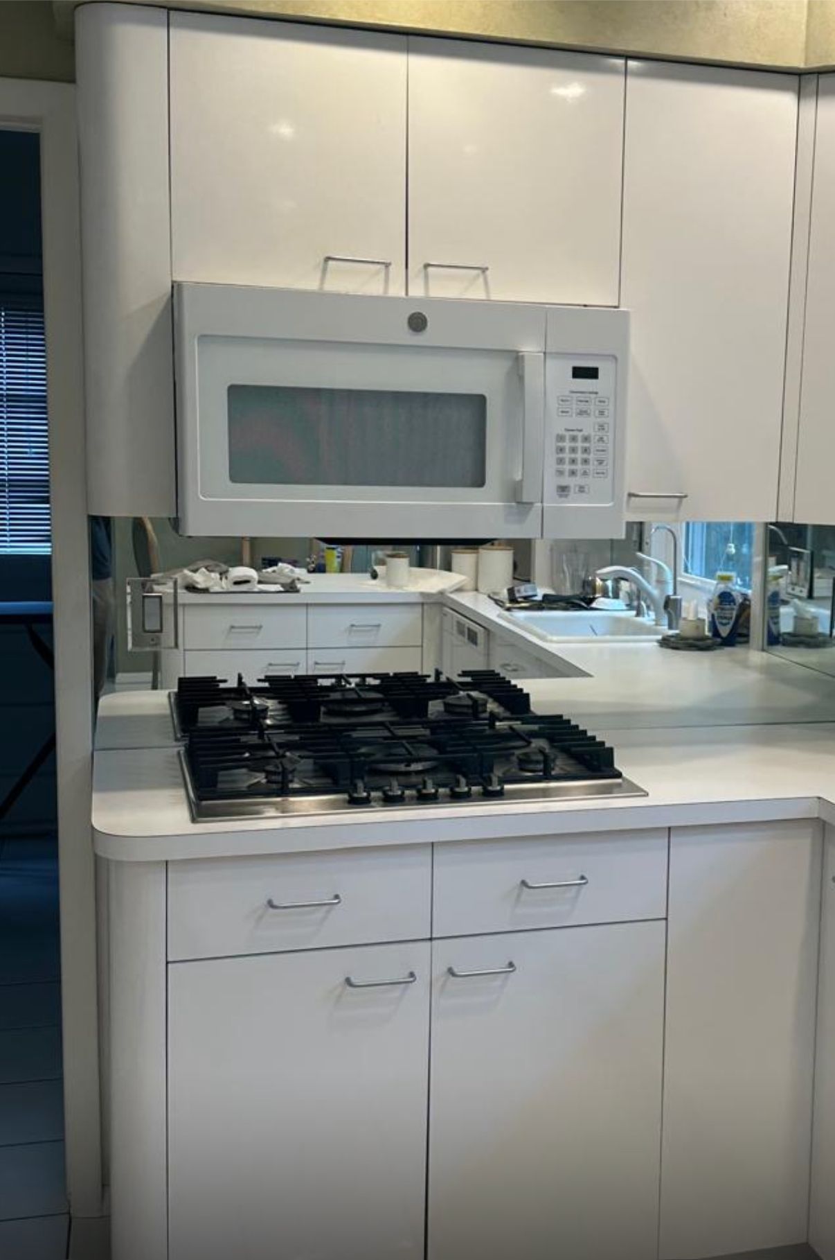 White kitchen with a countertop gas stove and over-the-range microwave below white cabinets.