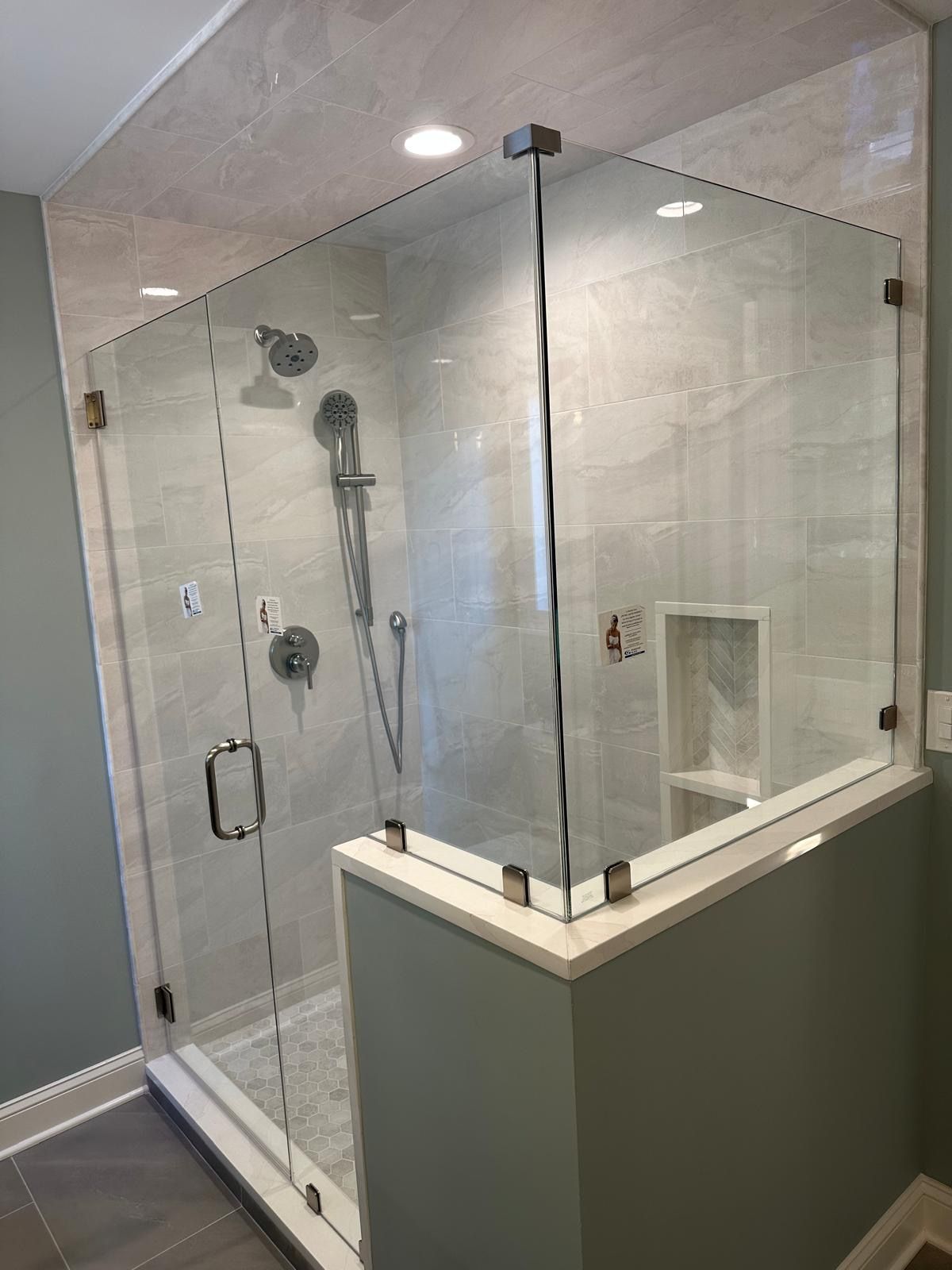 Modern glass-enclosed shower with tiled walls and a built-in bench in a bathroom