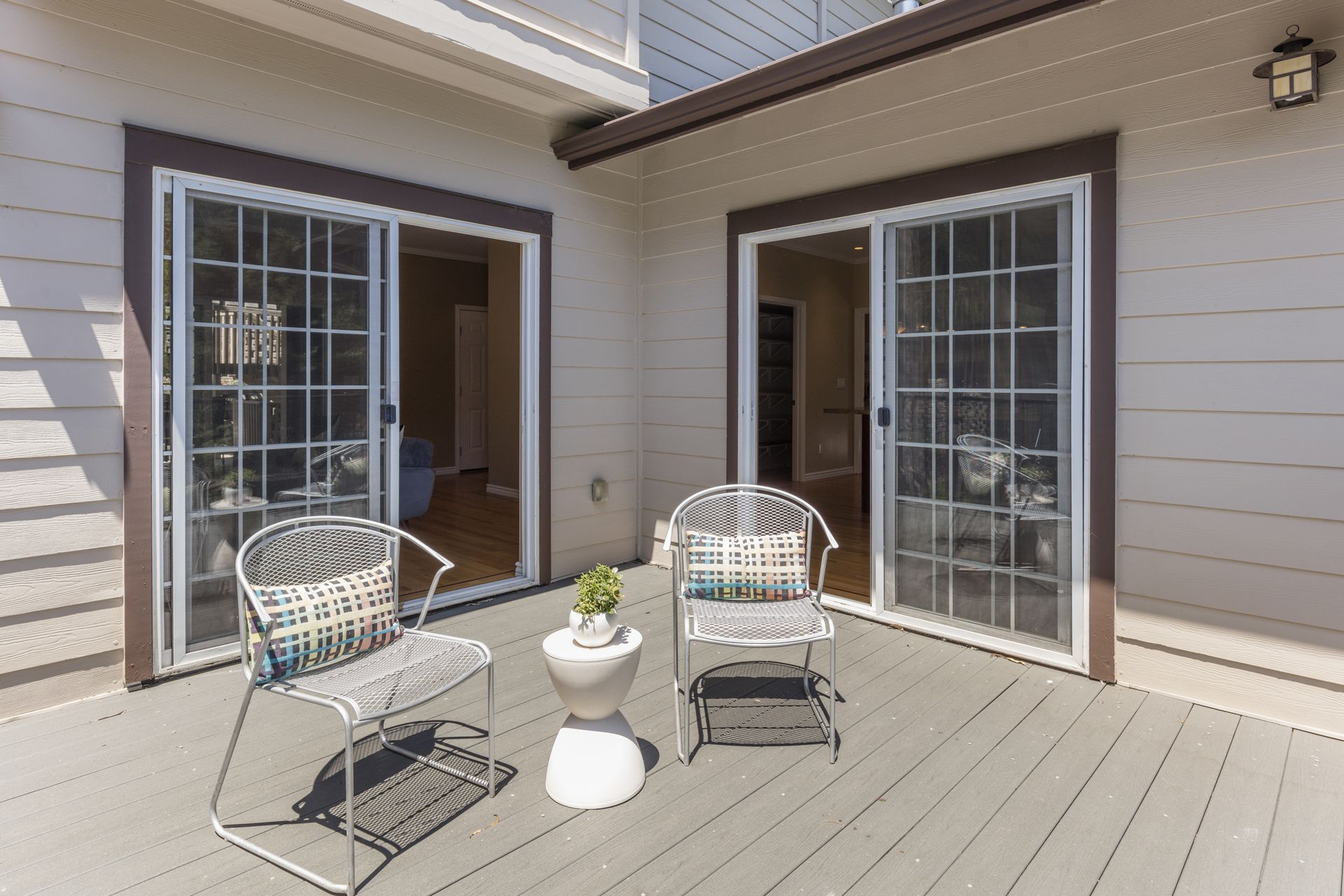 Outdoor patio with two white chairs, small table, and open French doors leading indoors