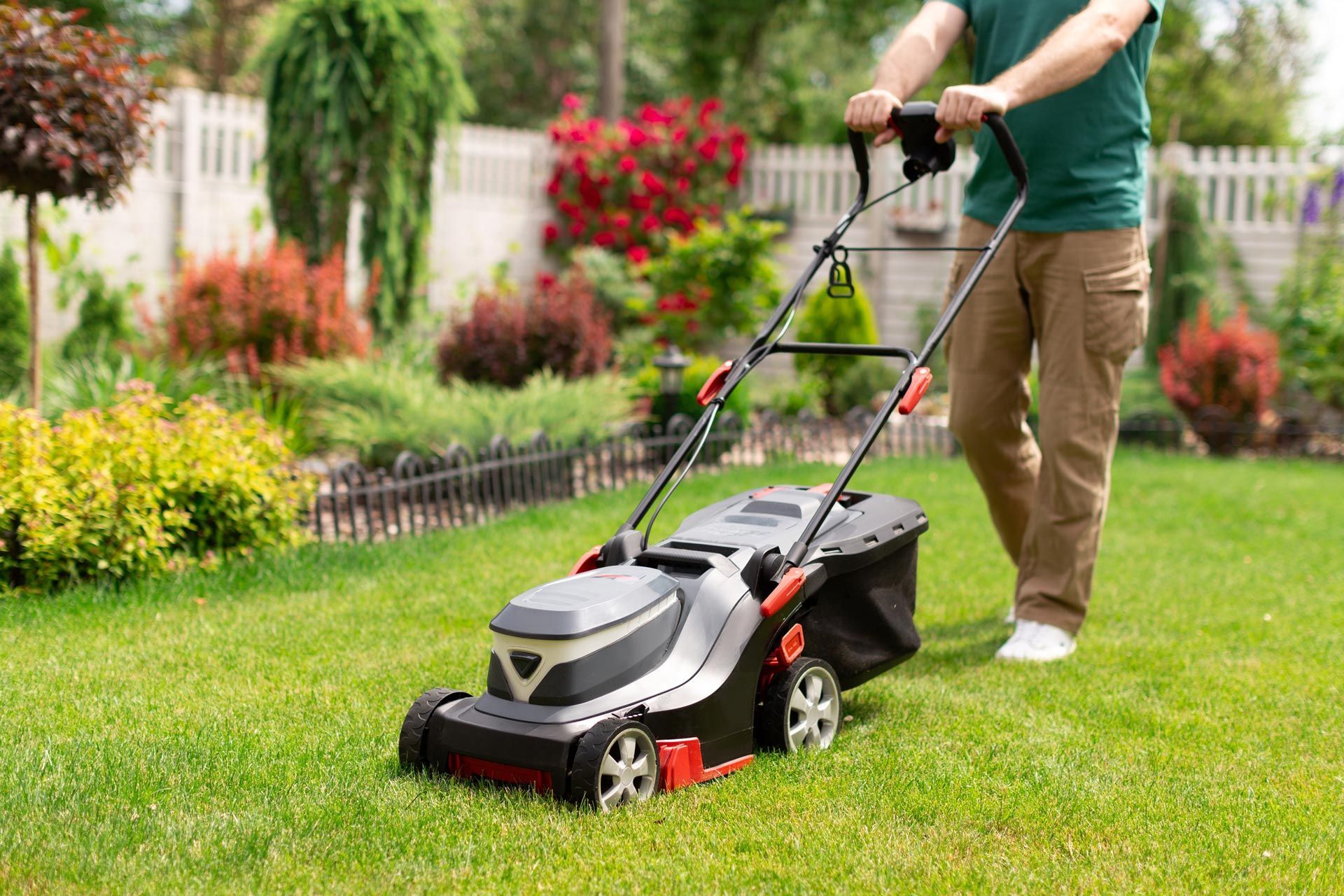 A man is using a lawn mower to cut the grass in his backyard