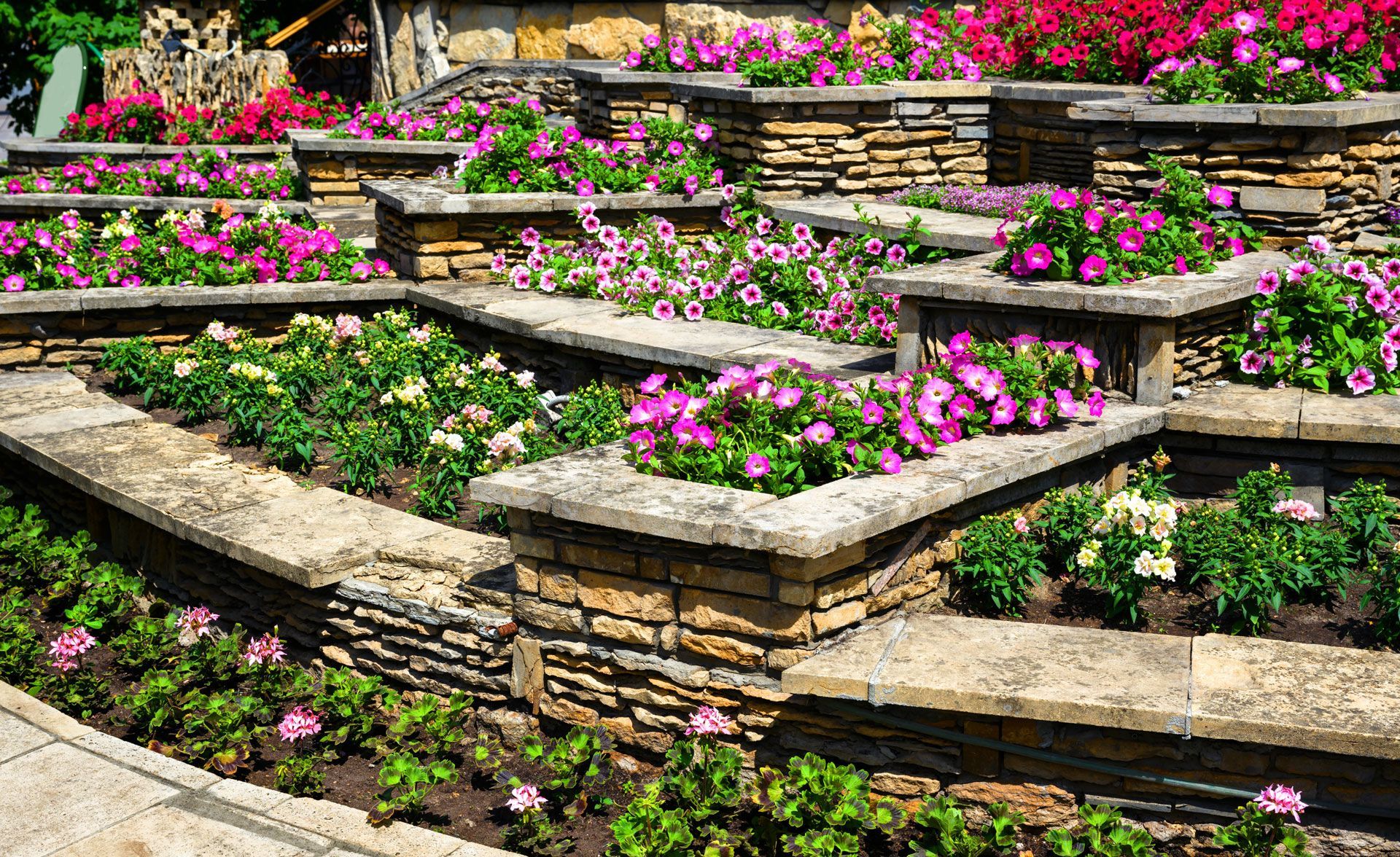 Stone tiered flower garden with vibrant pink, white, and green flowers.