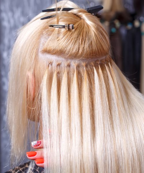 a woman is getting her hair done with extensions