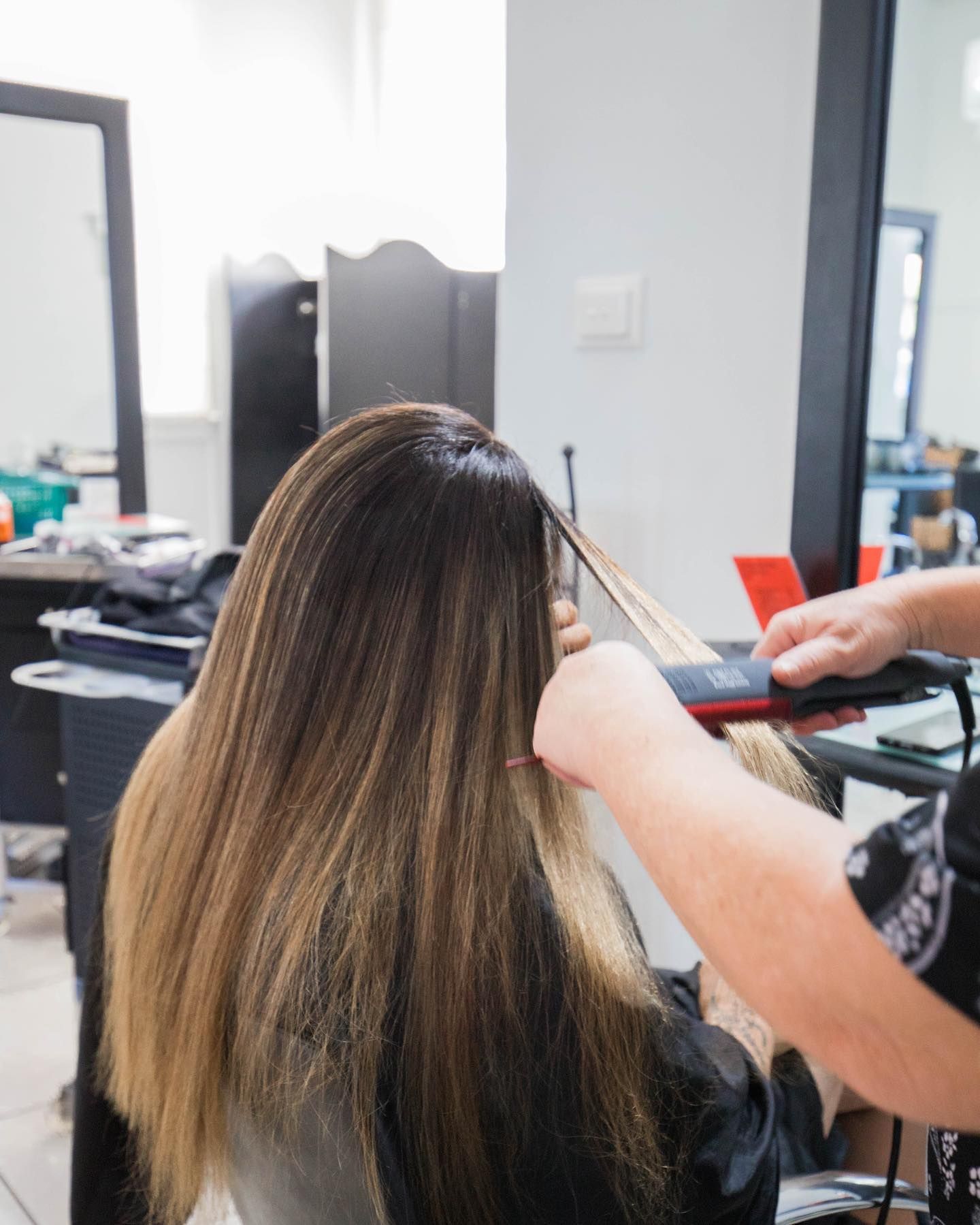 a woman is getting her hair straightened by a hairdresser - hair straightening Kingaroy