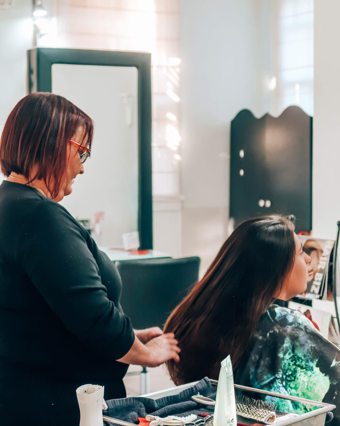a woman is getting her hair styled by a hairdresser - hair straightening Kingaroy