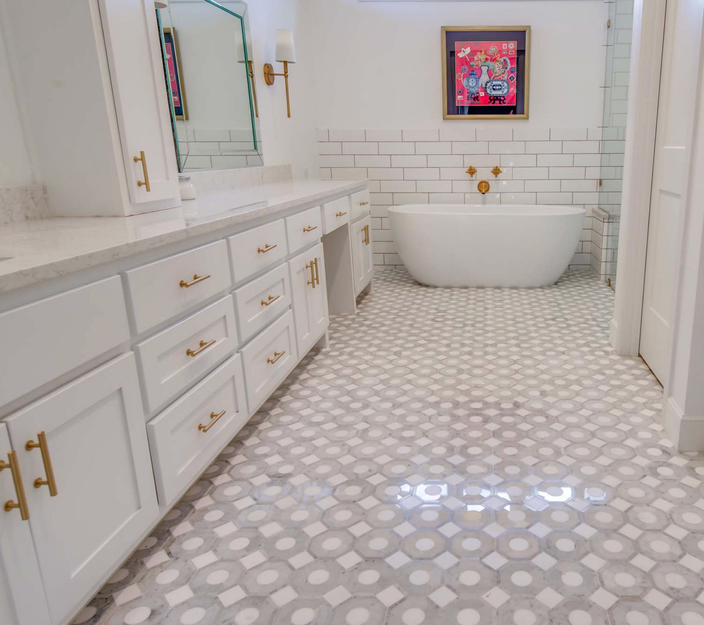 White bathroom with gray and white patterned floor tiles, white cabinets, and a freestanding tub.