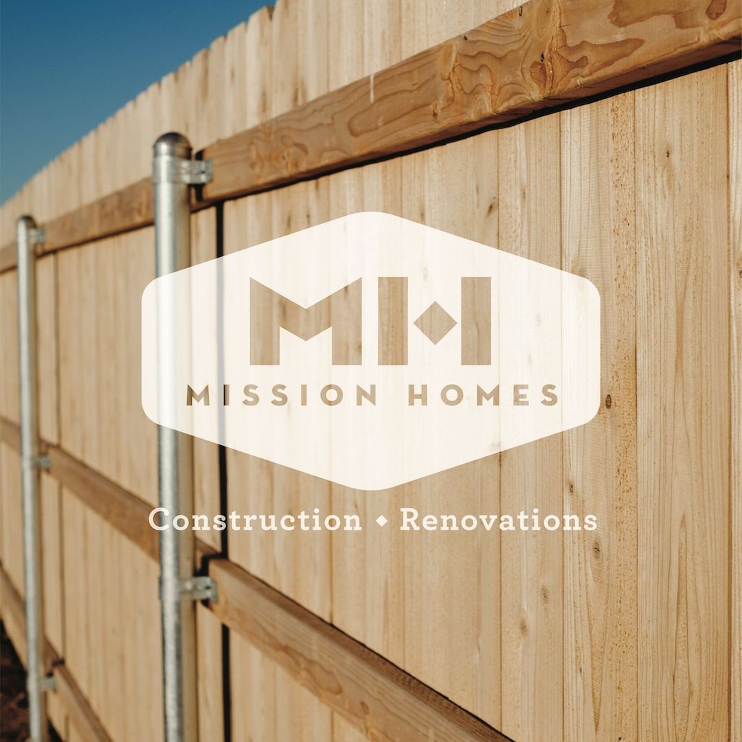 Wooden fence with the Mission Homes logo, text