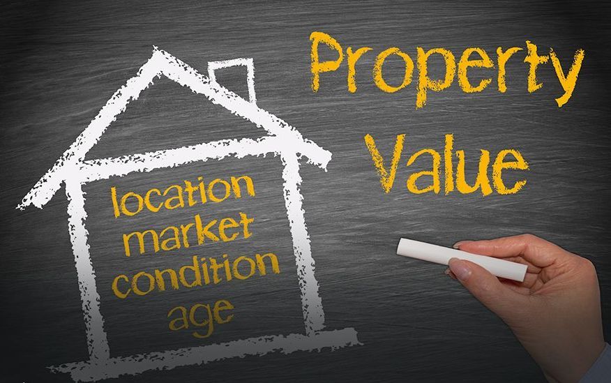 A person is writing on a blackboard about property value