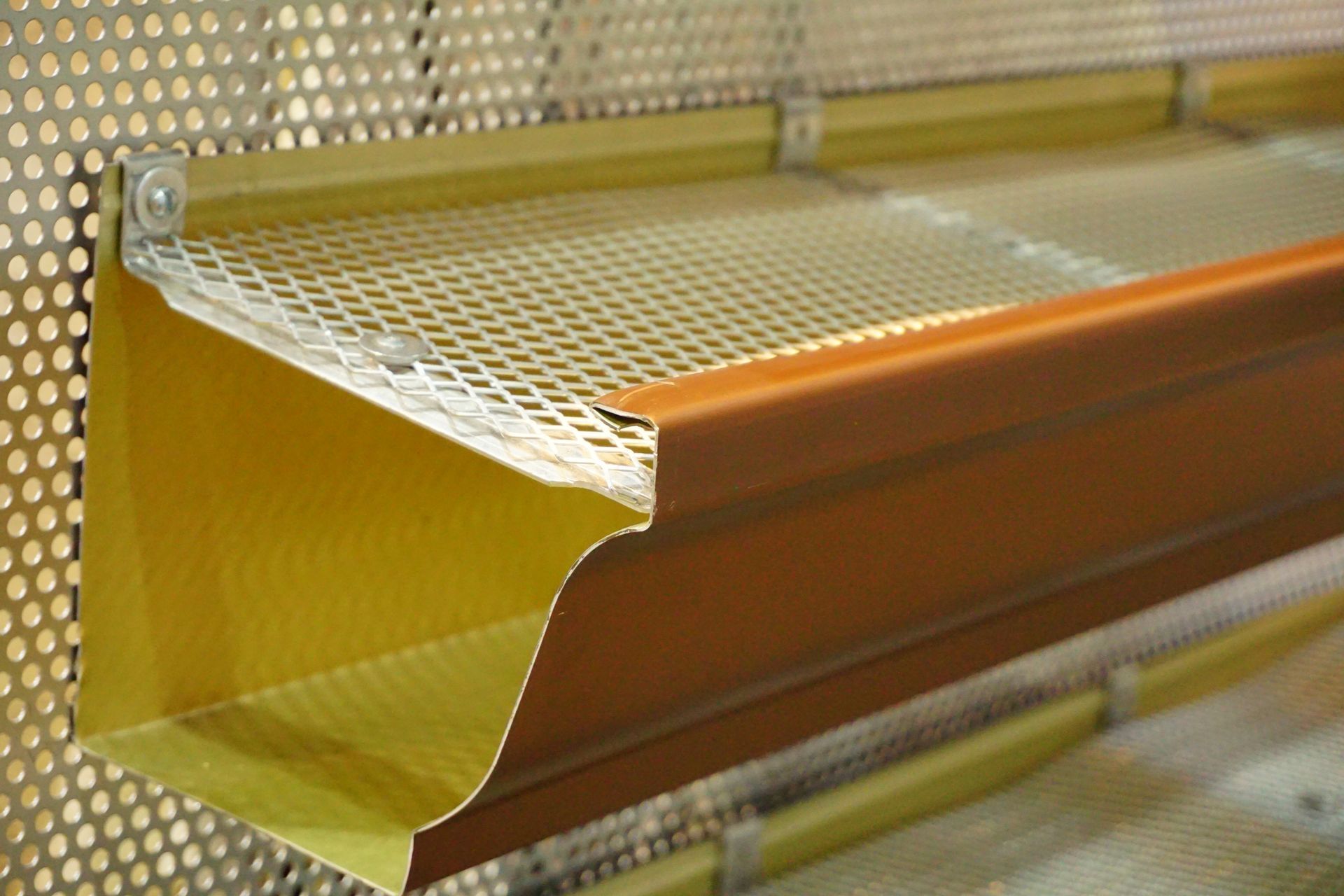 A close up of a gutter on a perforated wall.