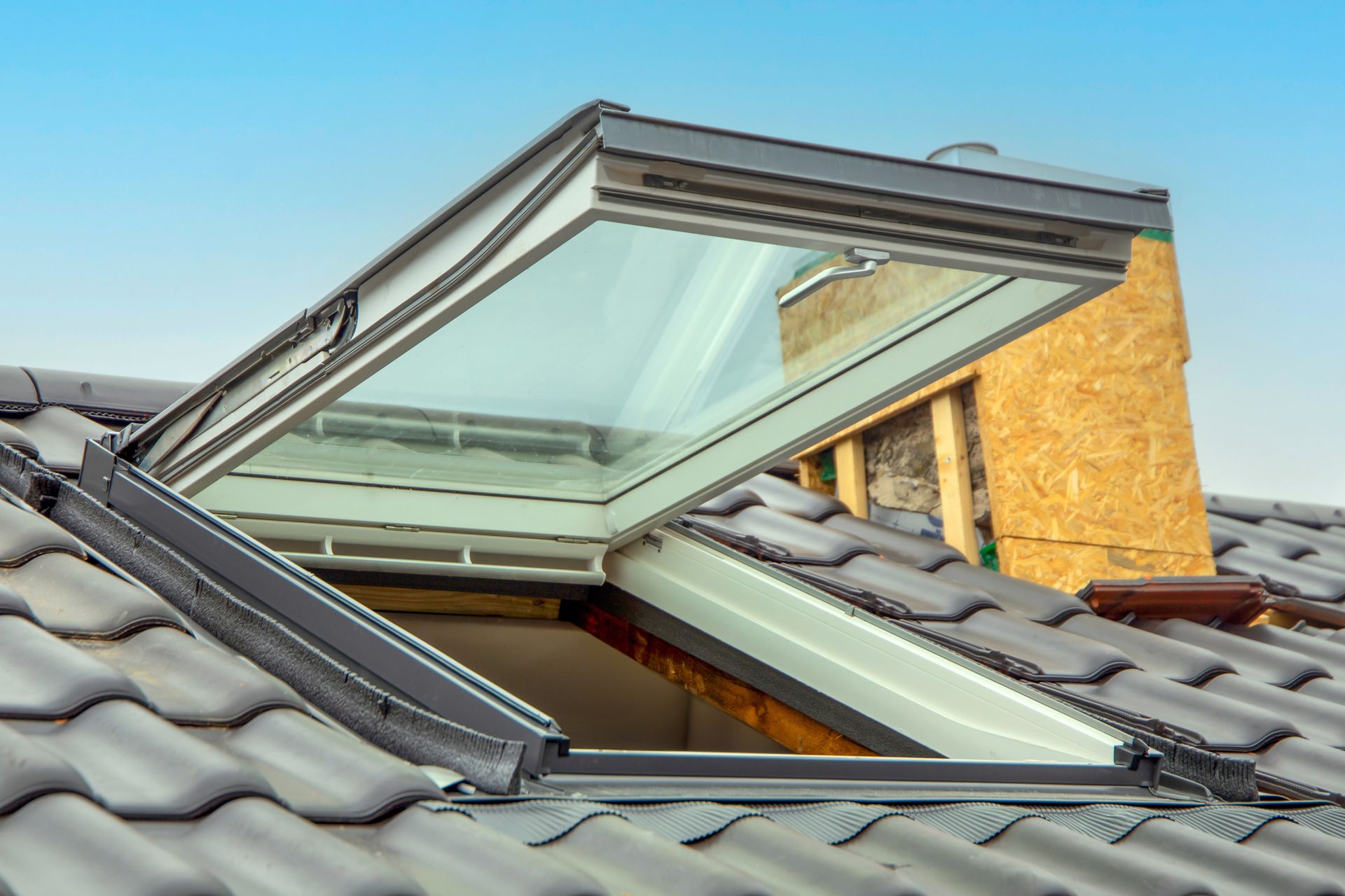 A skylight is open on the roof of a house.