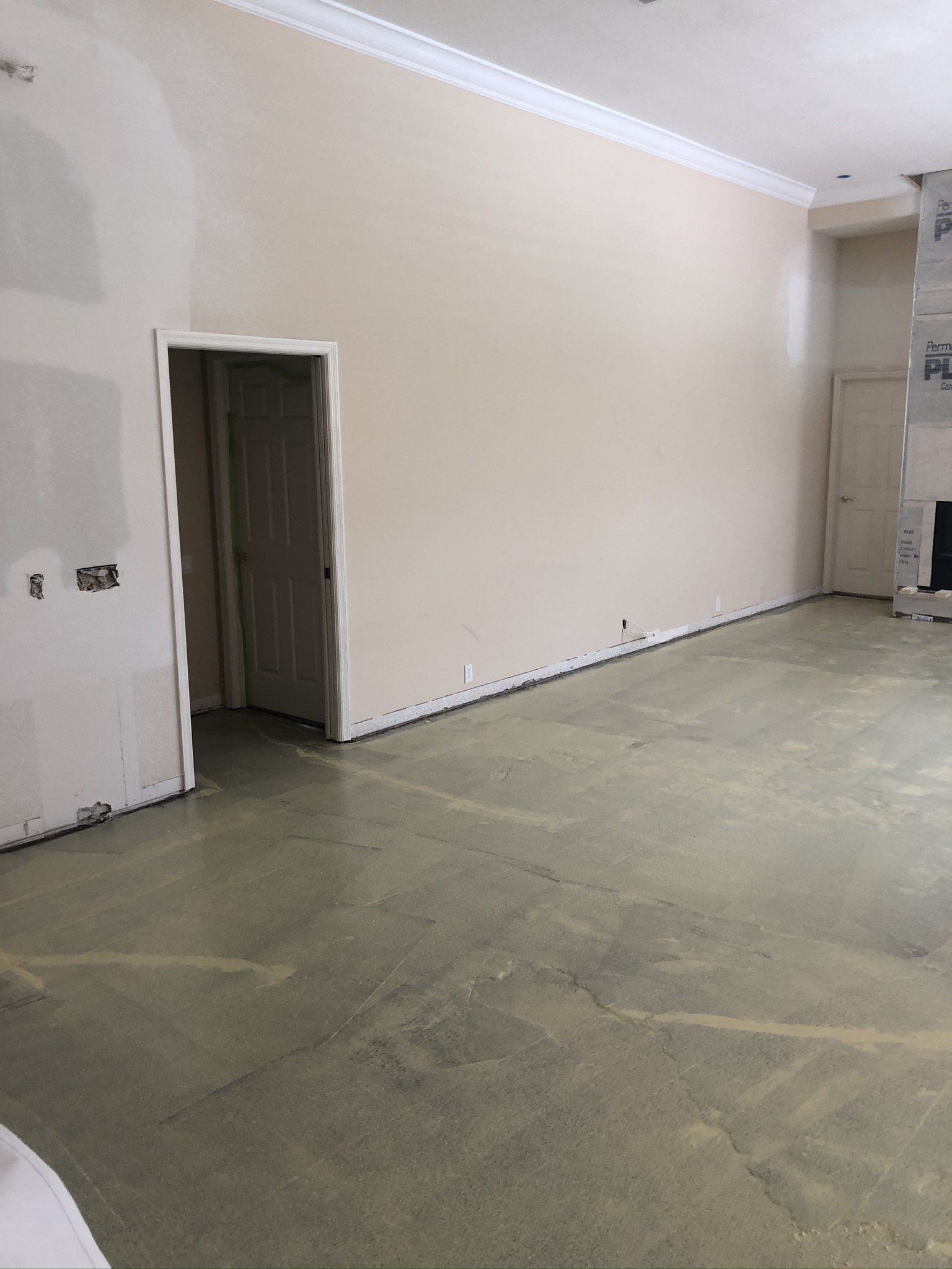Empty beige room with unfinished concrete floor and two open doorways