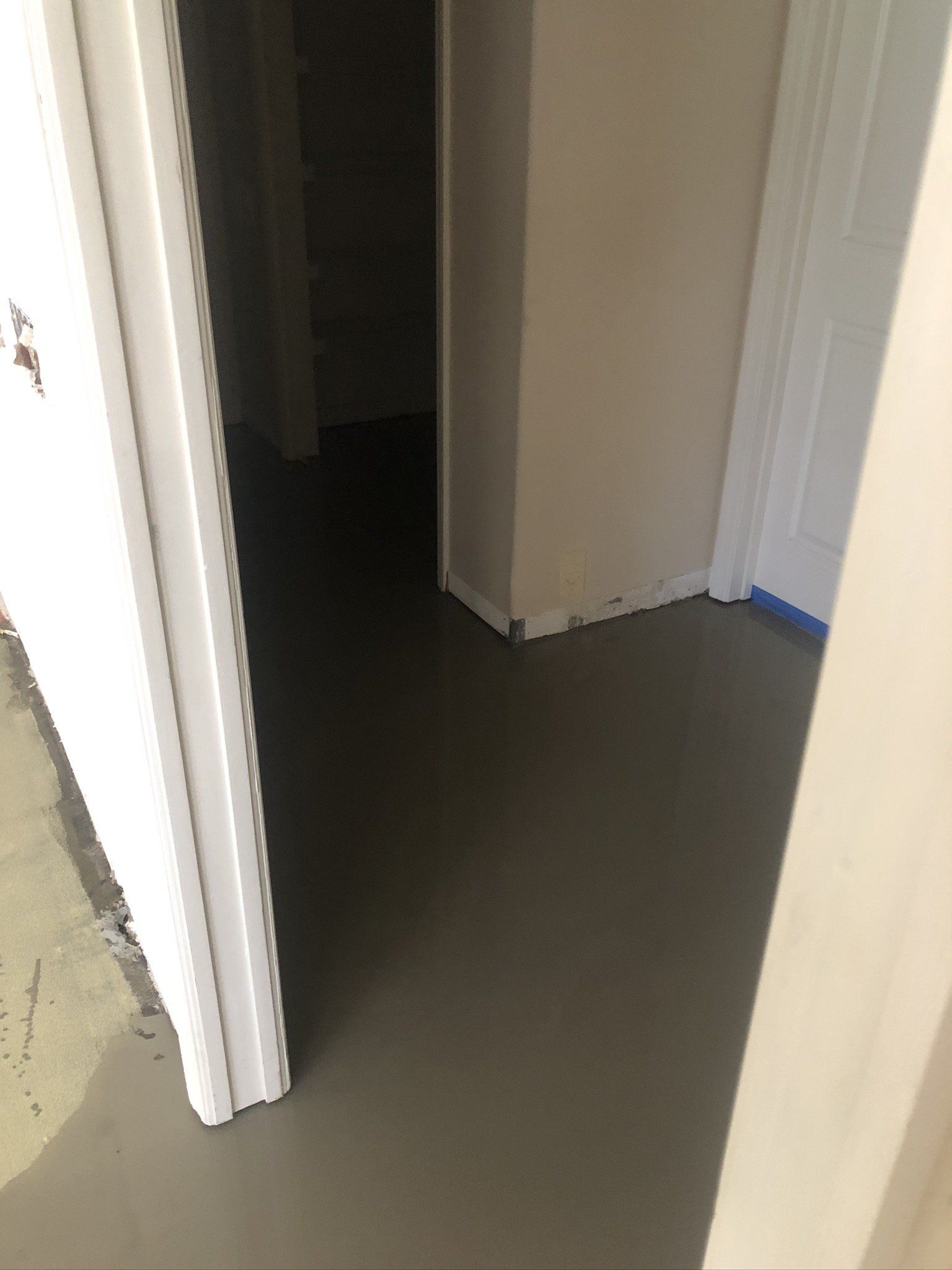 Dim hallway with open doorways and a dark floor indoors