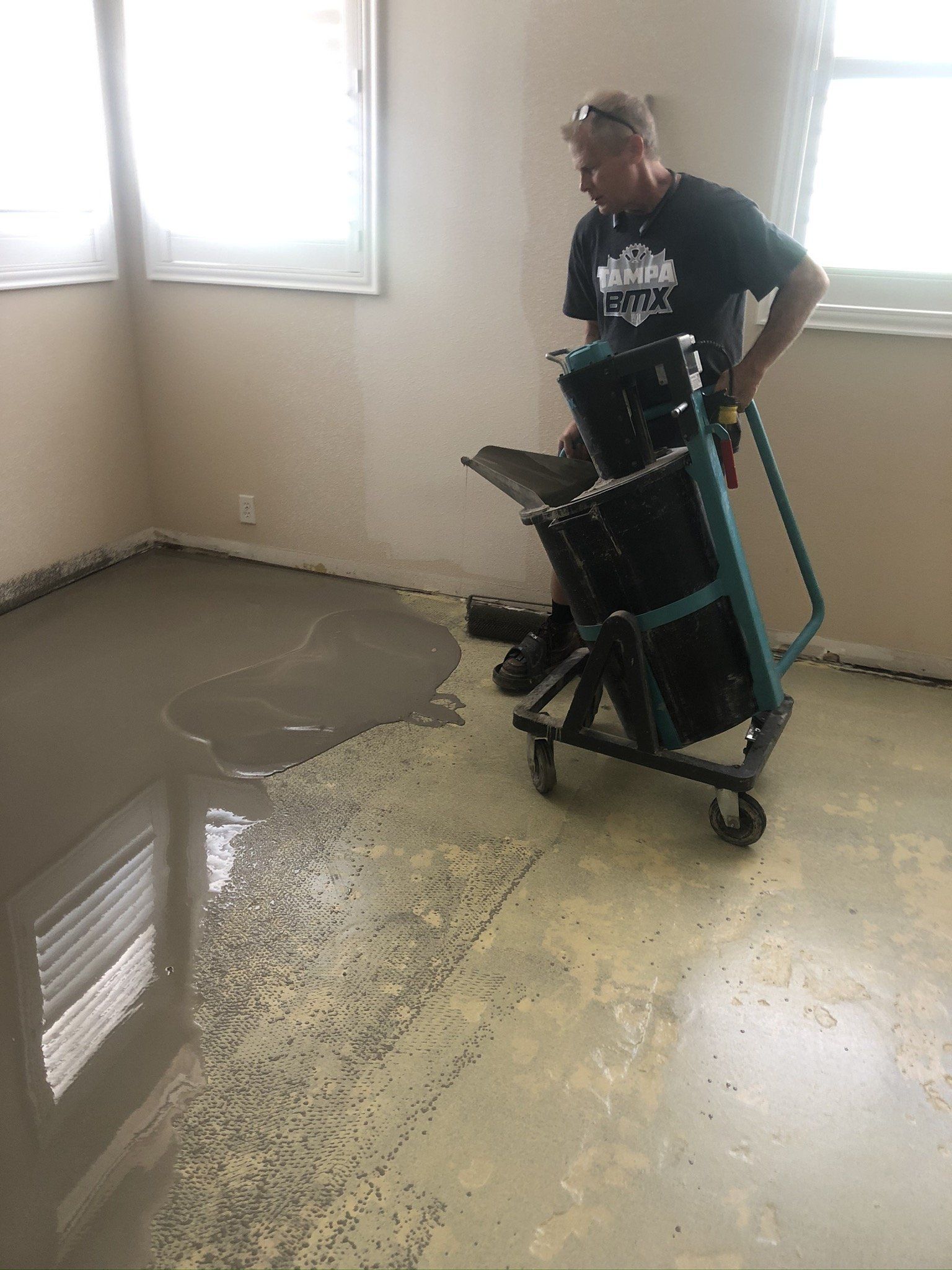 Person moving a wet floor machine over a wet, reflective indoor floor near a window