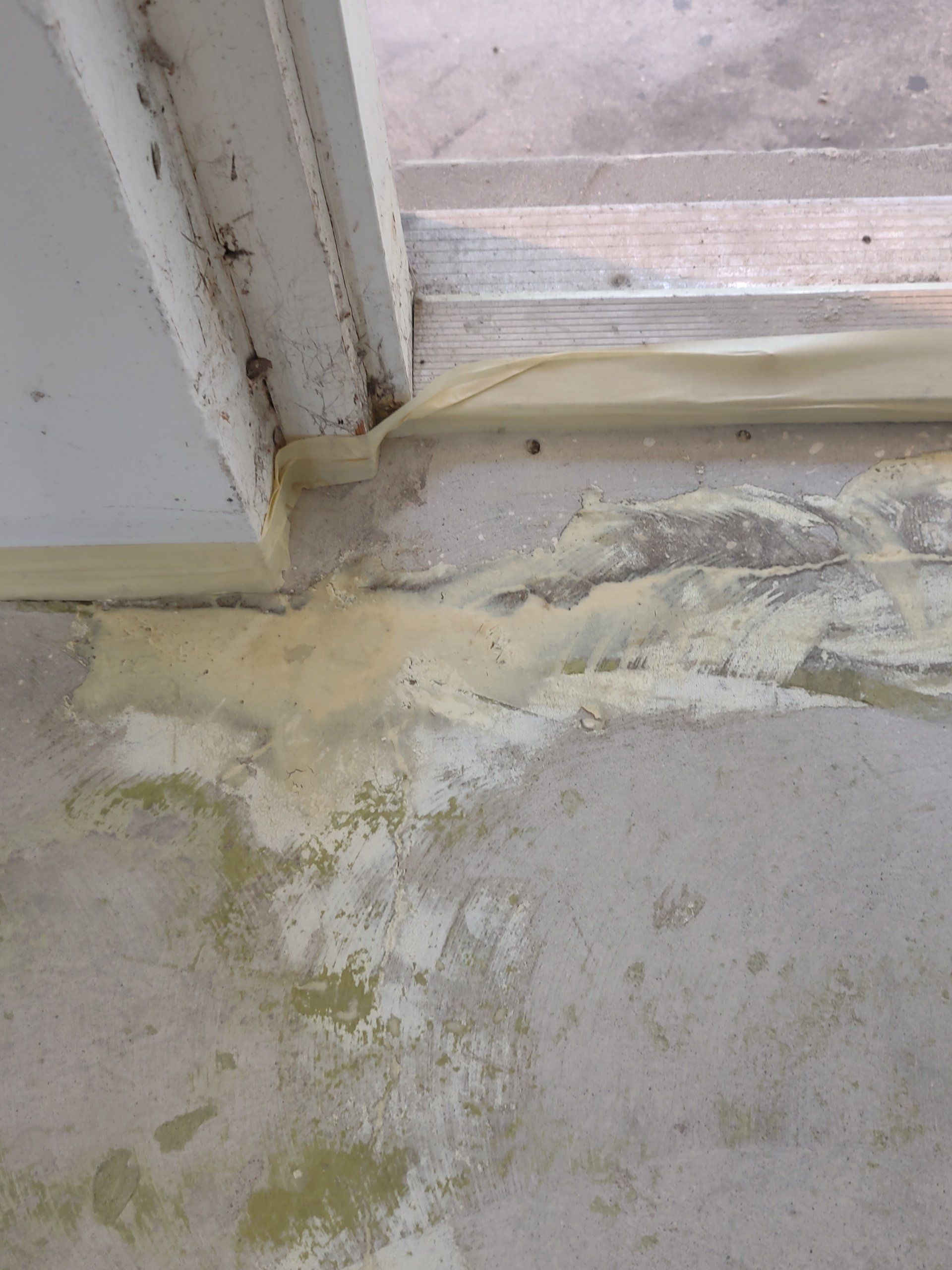 Damaged wall and floor corner with peeling paint and water stains near a window frame