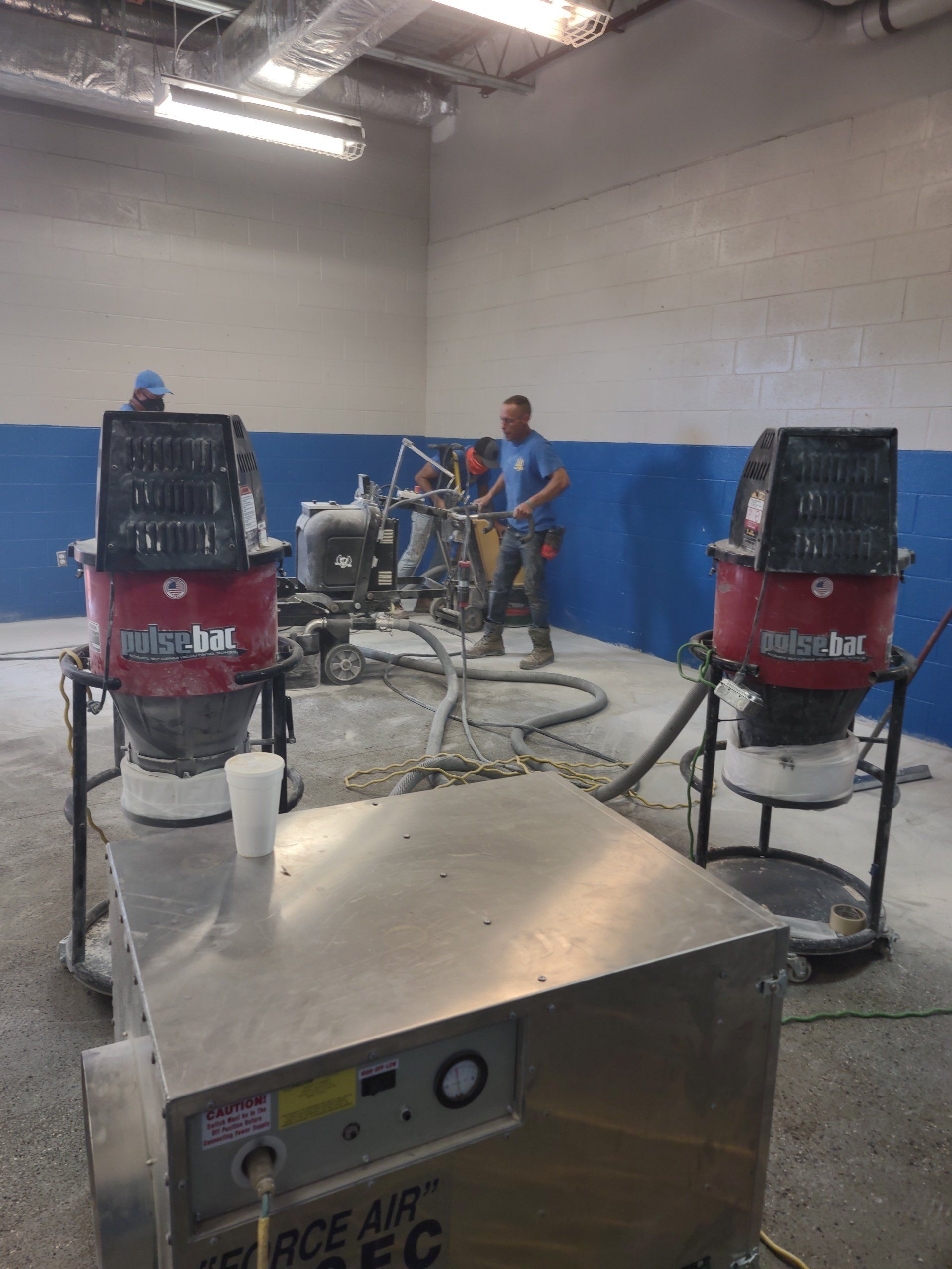 Workshop with two red air compressors and a worker using a machine in the background