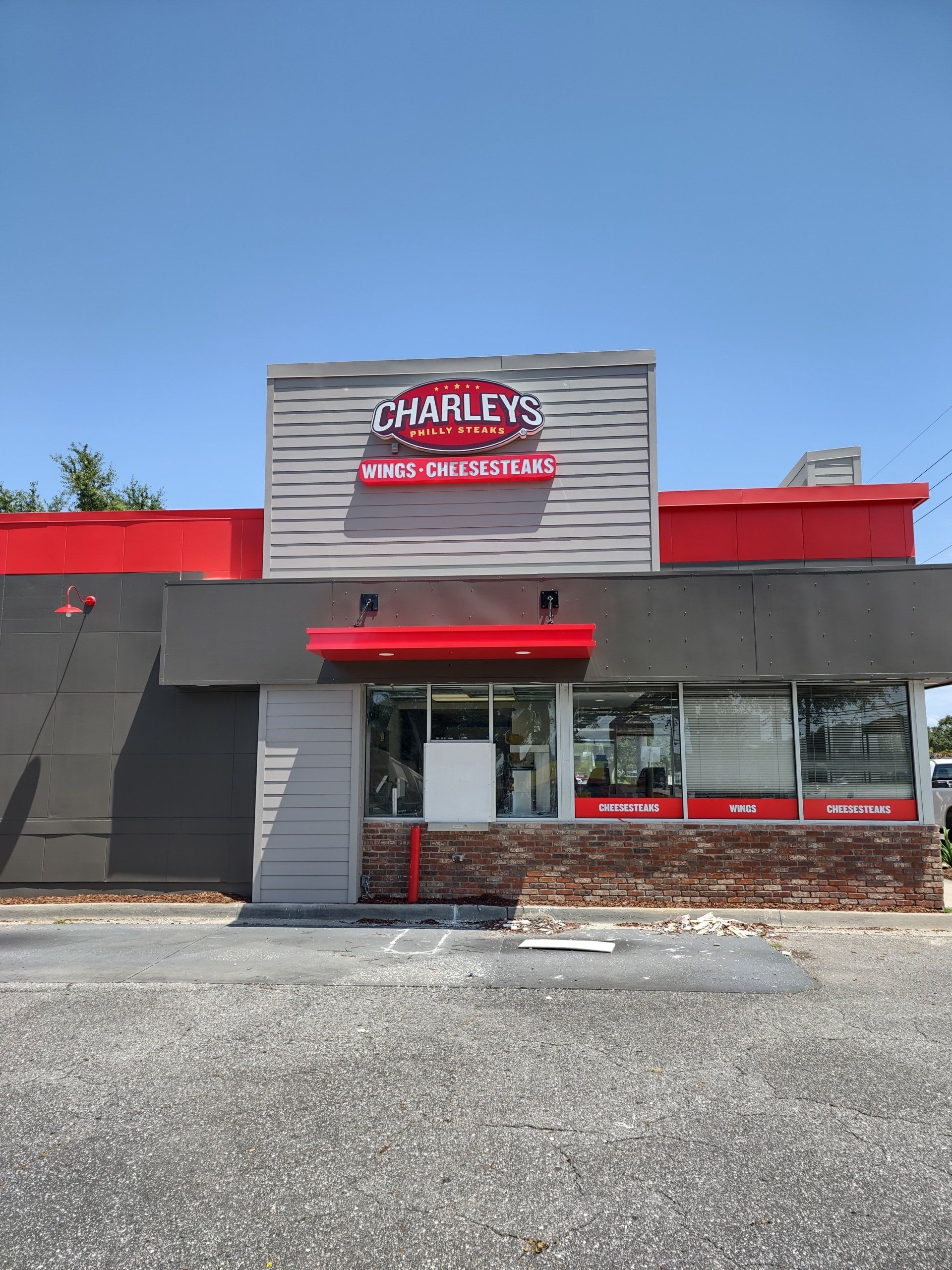 Harley-Davidson motorcycle dealership with red awning and gray facade under a clear blue sky