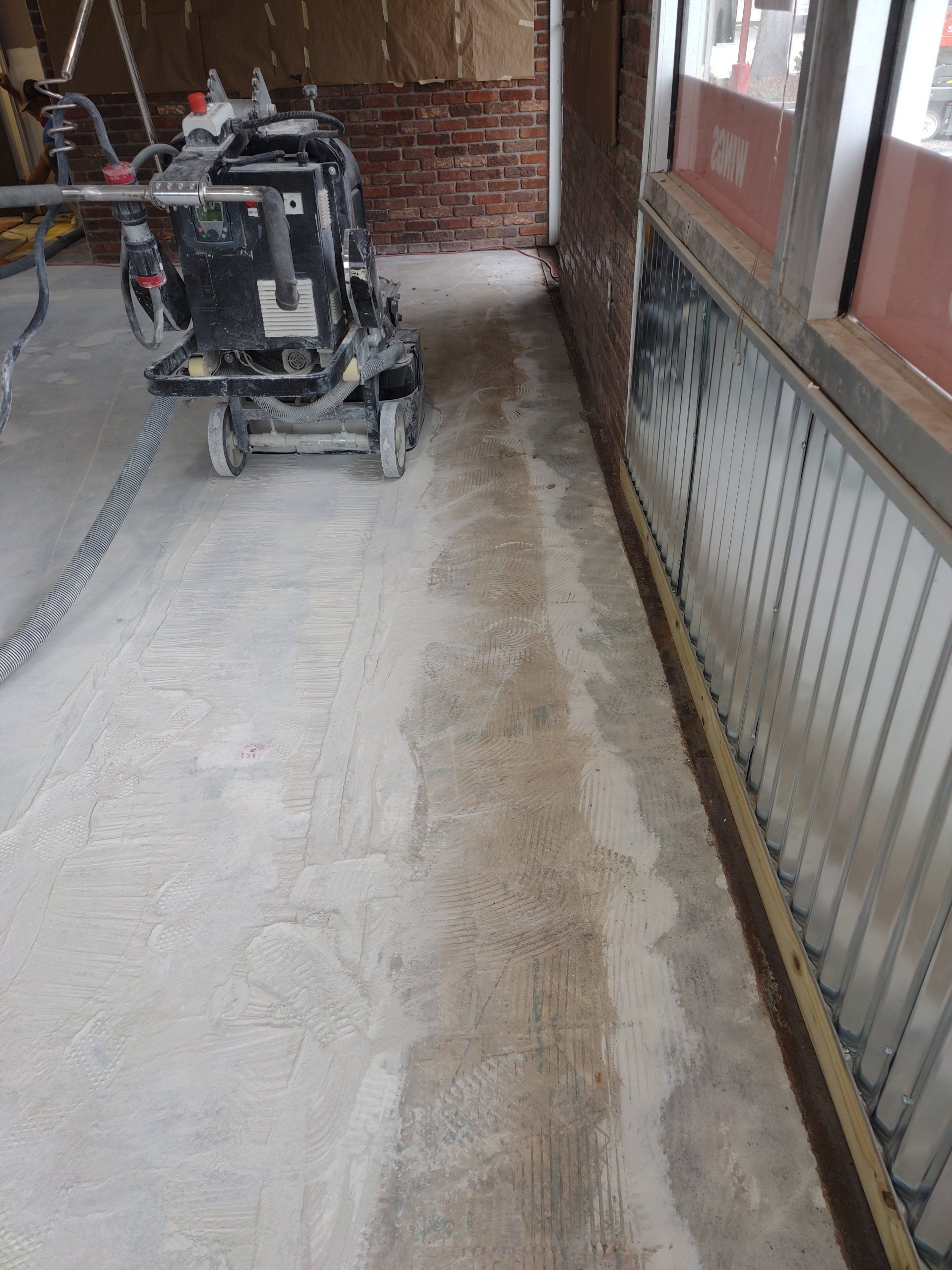 Dusty construction corridor with a mobility device parked on the left and windows lining the right wall.