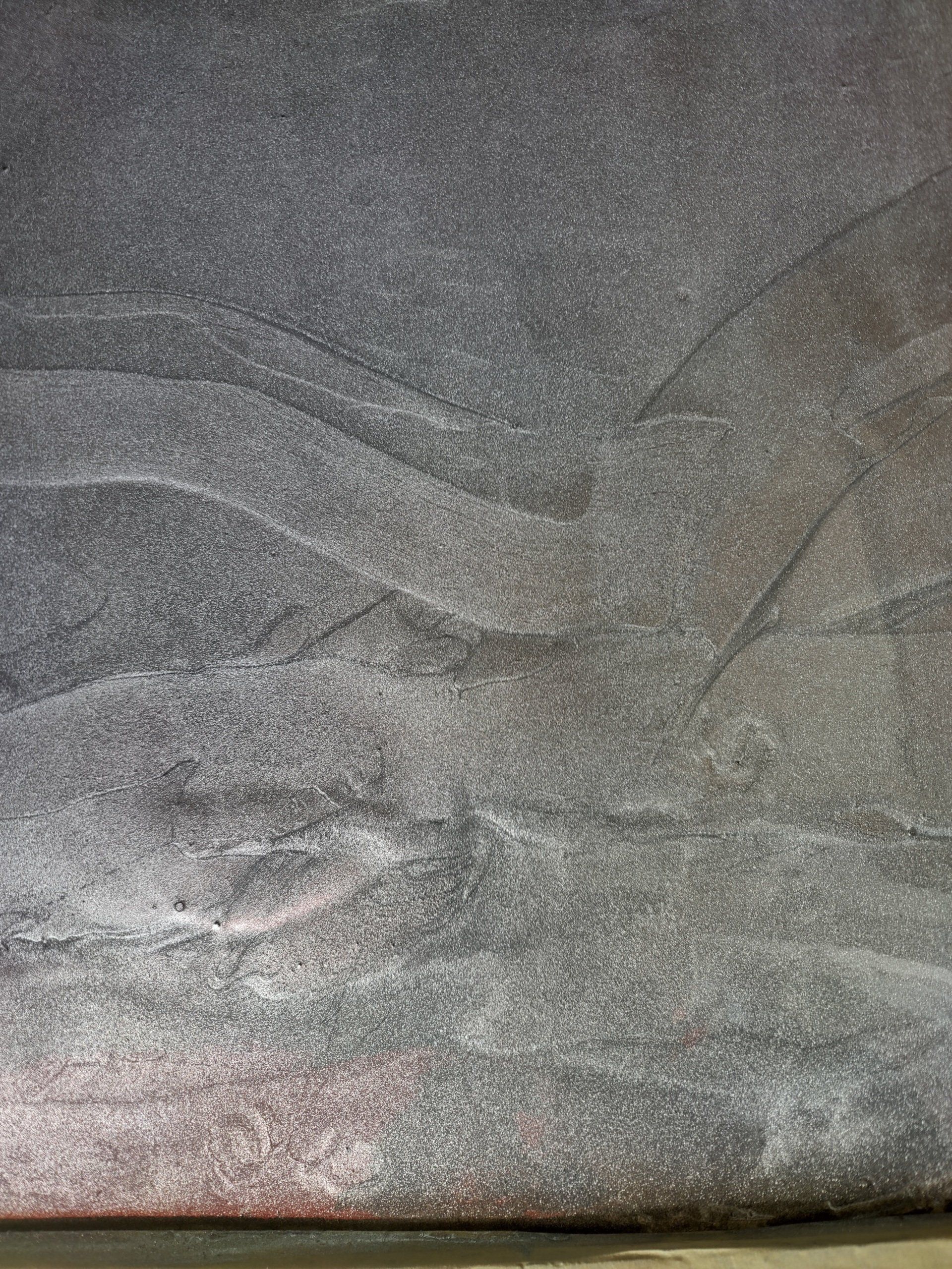 Close-up of a dark gray textured fabric with subtle wavy patterns.