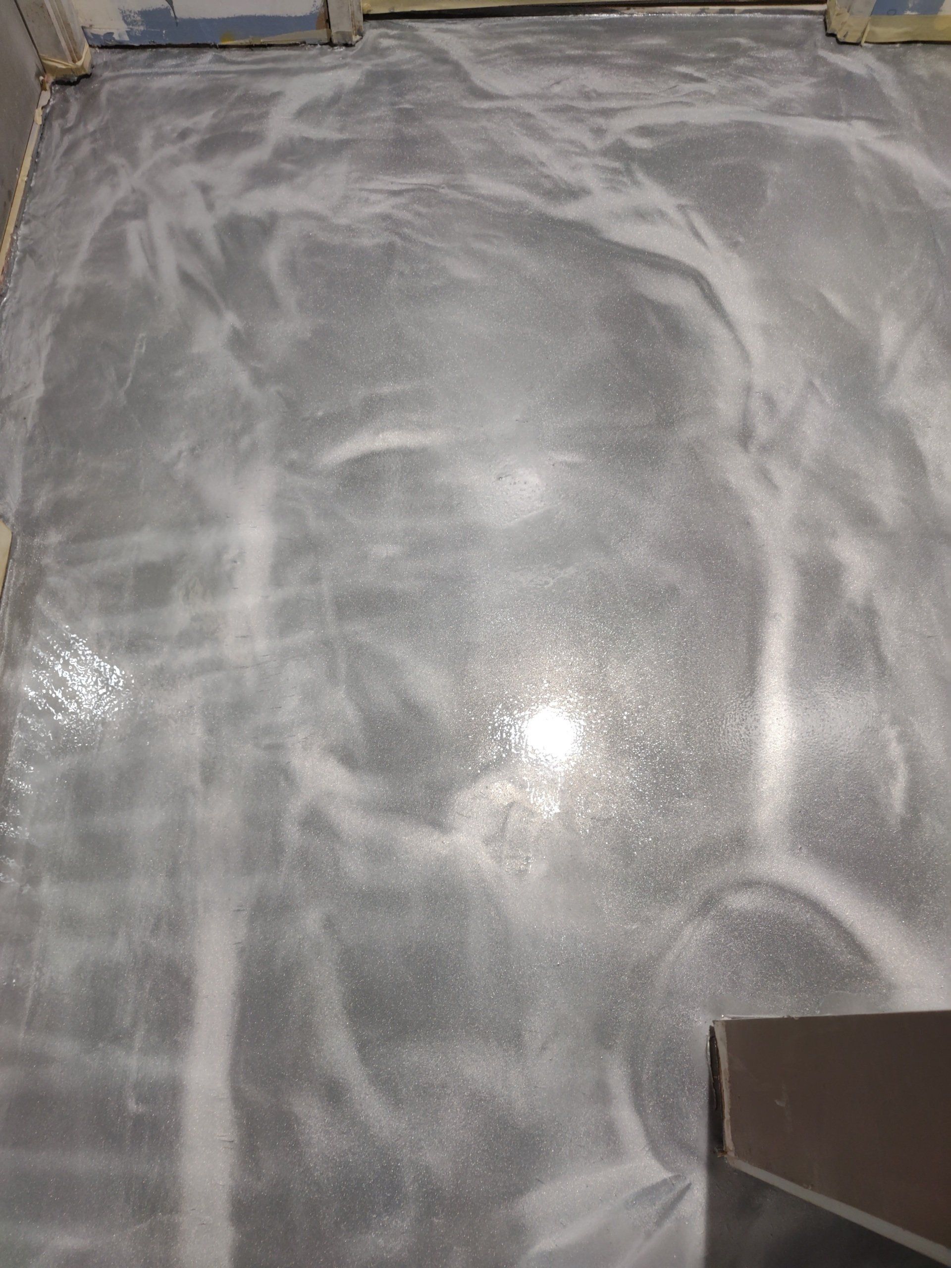 Polished gray concrete floor with white streaks and a dark corner edge