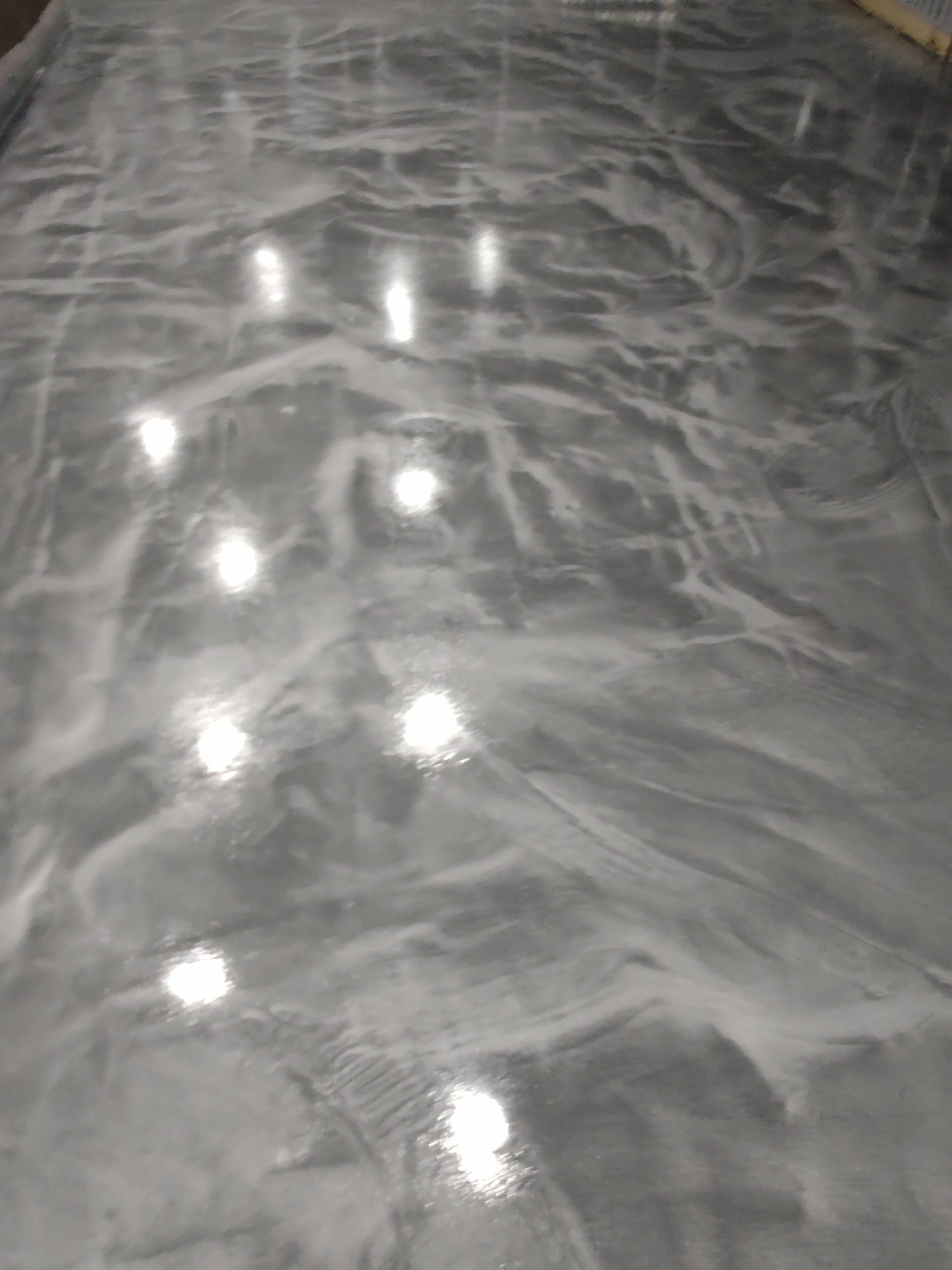 Shiny gray textured surface with bright reflected lights, viewed close up.