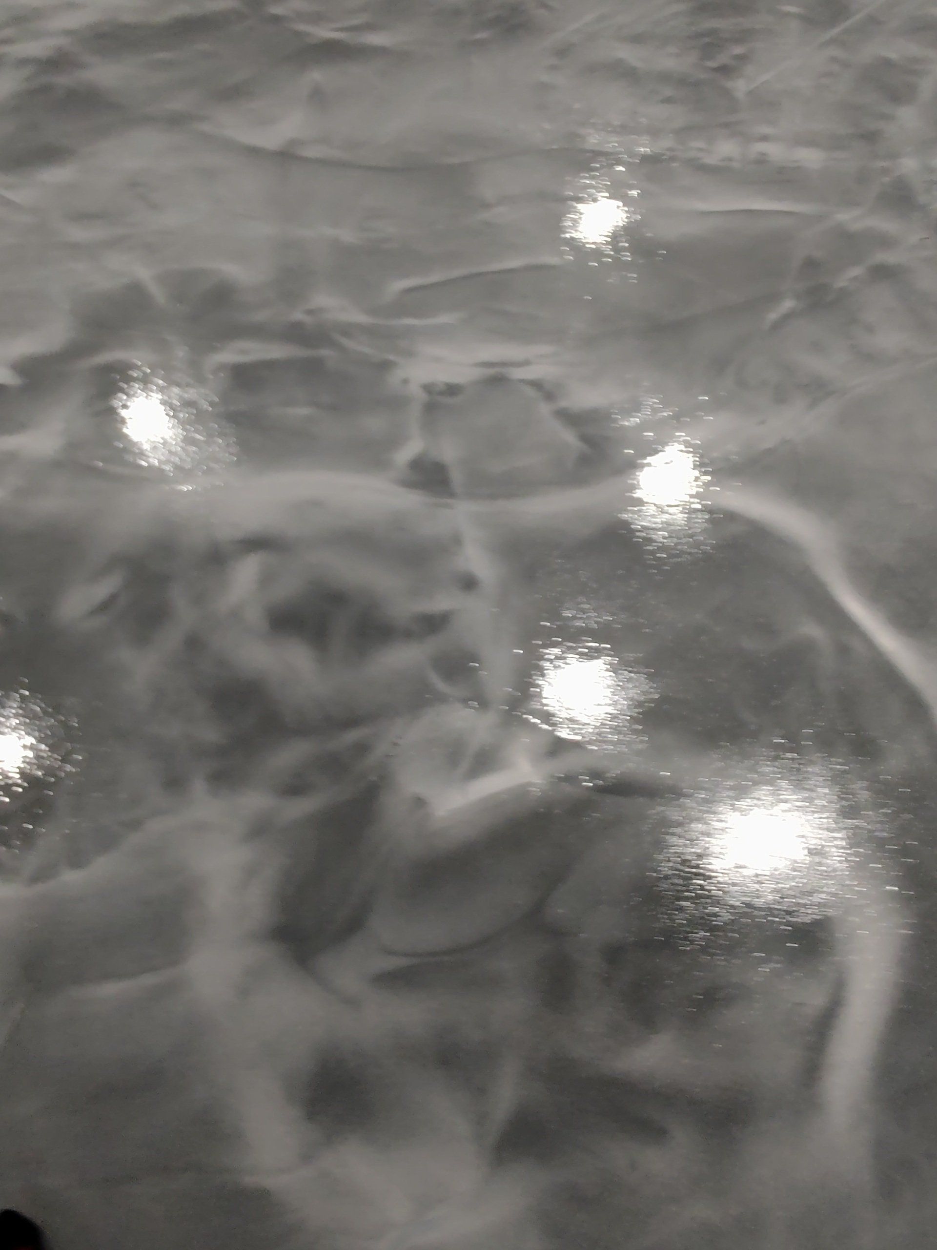 Rippling gray water with bright white reflections of overhead lights
