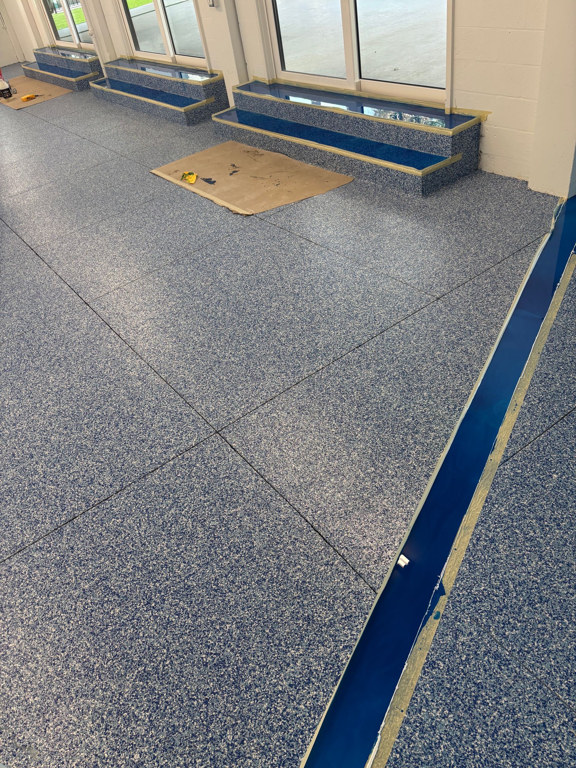 Empty carpeted waiting area with bench seating and large windows