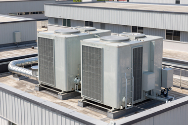 Two rooftop HVAC units on a commercial building with white and gray exteriors.