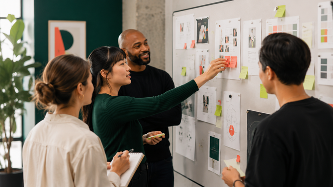 Team meeting around a glass wall covered with colorful sticky notes in a modern office
