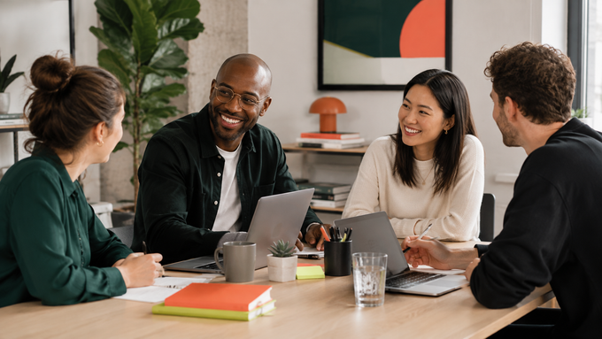 Team meeting in a bright office, one person presenting at a whiteboard while others listen and take notes.