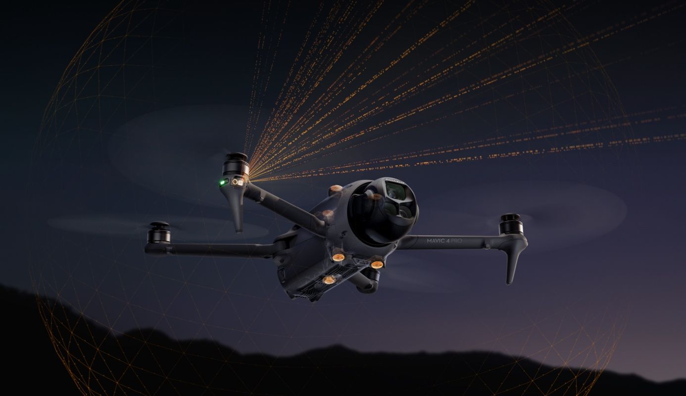 A drone in flight at night, emitting orange light trails from its rotors against a dark landscape.