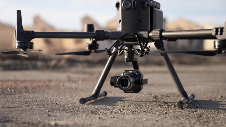 Drone flying over mountains at sunset, with cloudy sky and rugged peaks in the background